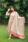 An indian woman wearing a printed staple tussar gold A line kurta and trousers with gold chanderi dupatta. The dupatta has red calligraphy motifs appliqued at the borders of  the dupatta. The is looking  a bit towards her right.
