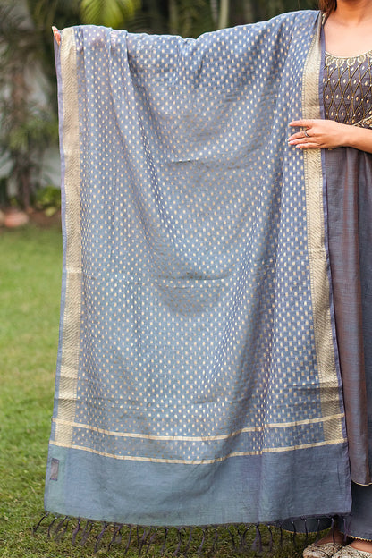 Indian model holding a grey chanderi dupatta with zari banarasi work and small geometric motifs.