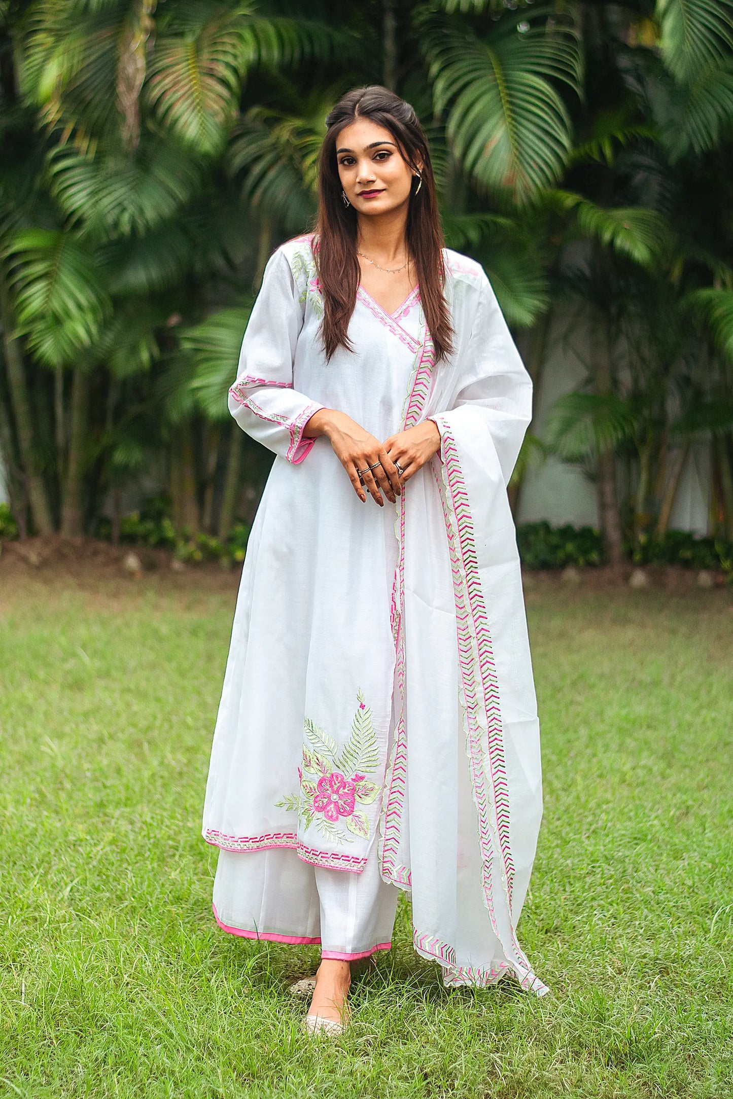 Indian model in a white chanderi angrakha and dupatta with pink embroidered flowers and green leaves, paired with white palazzo.