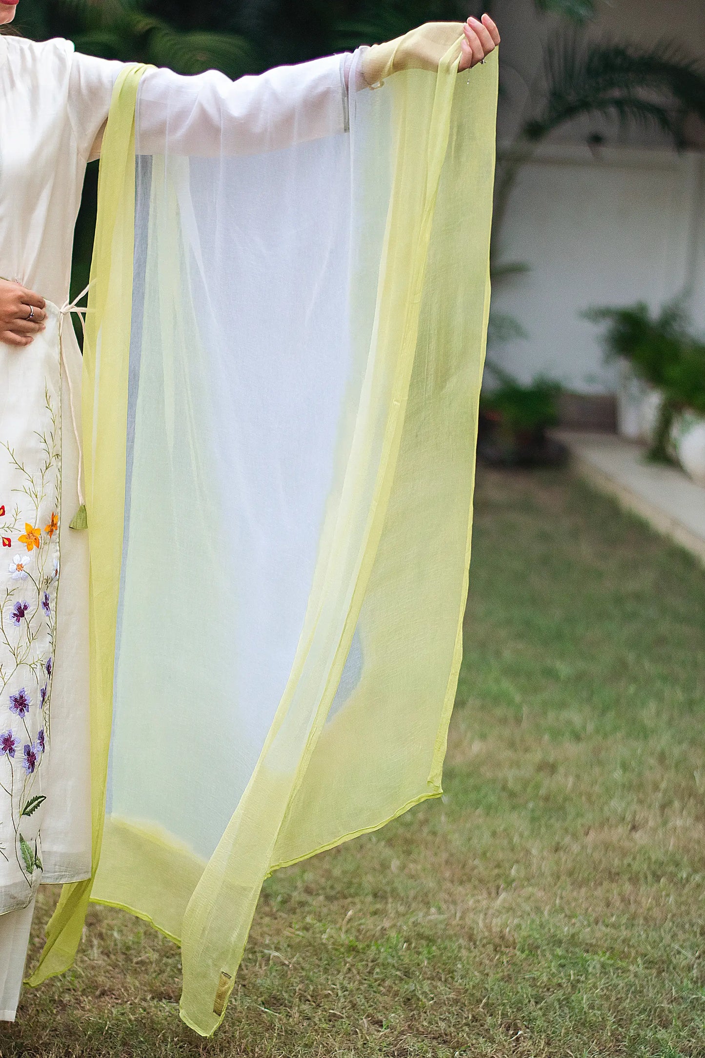 Indian model holding a lightweight off-white and green chiffon dupatta, complementing the angrakha kurta set.