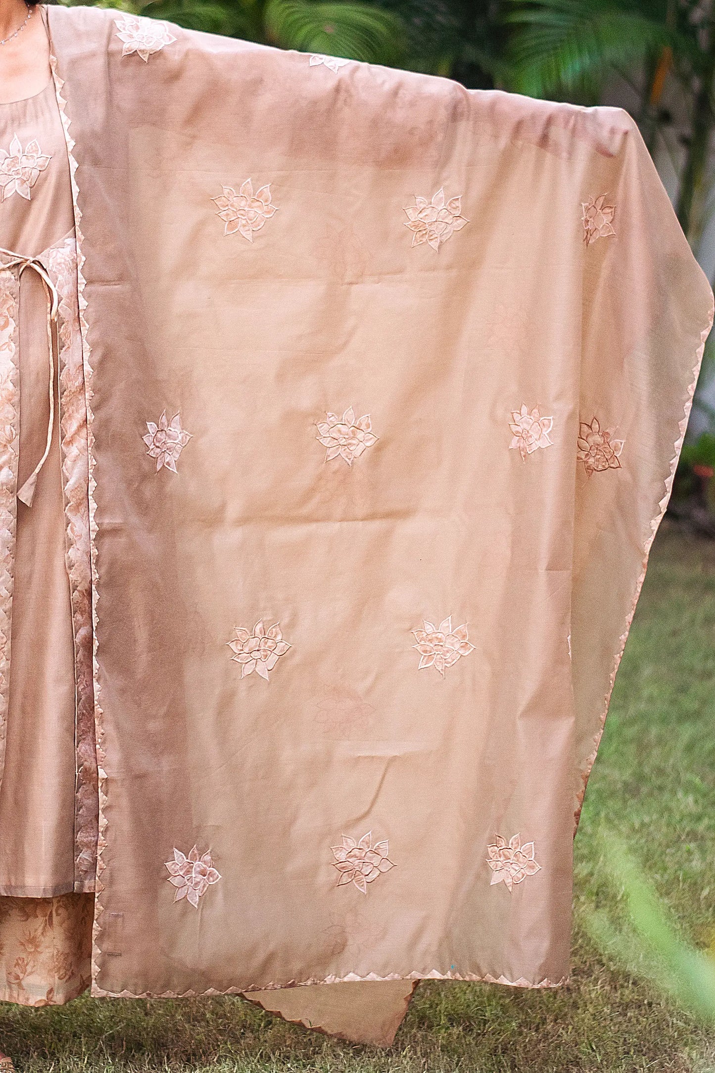 Detail of the beige chanderi dupatta adorned with beige patchwork flowers and kikri work, as styled by the model