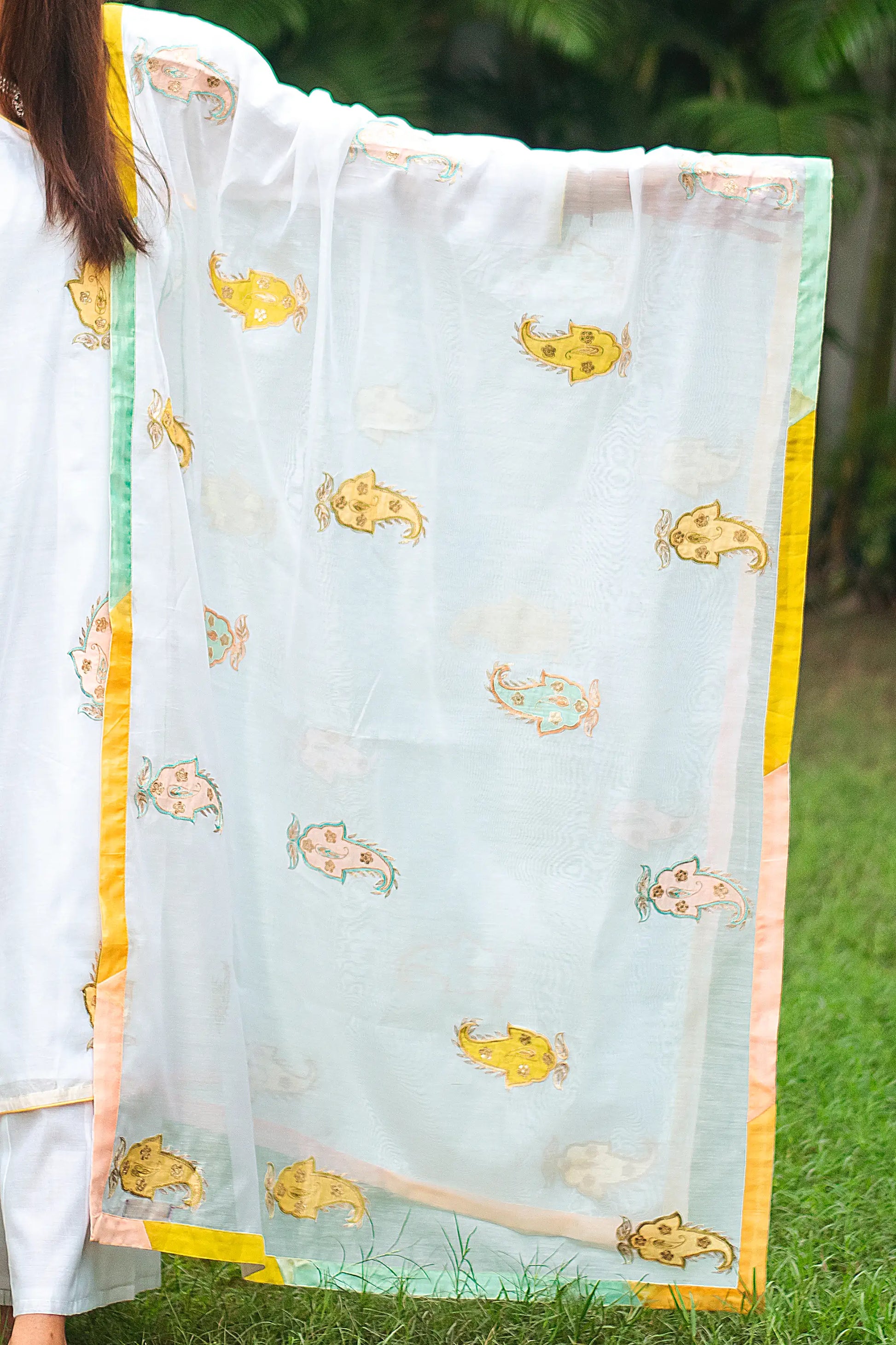 Indian model holding a white chanderi dupatta with kairi (paisley) patchwork.