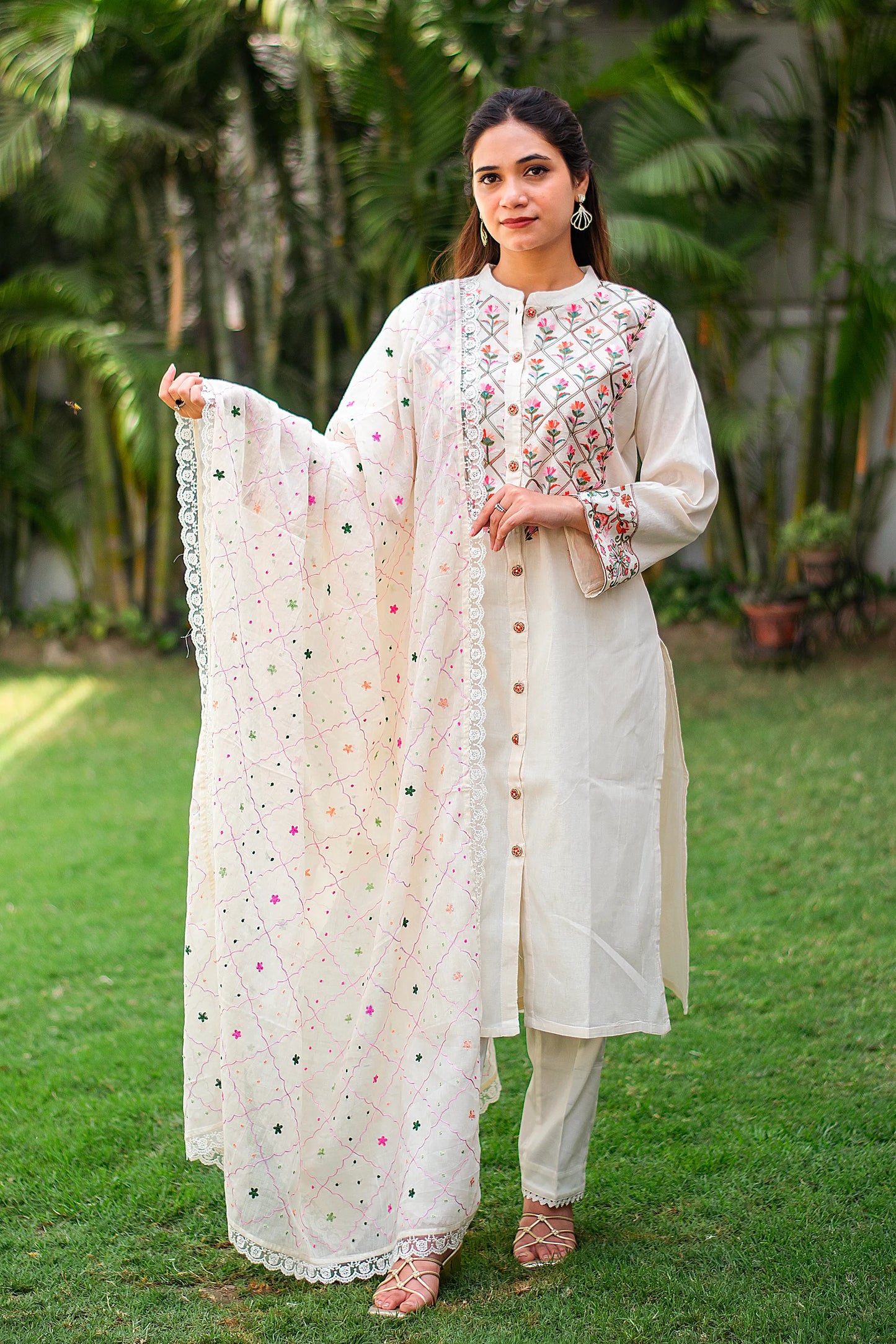 Indian girl wearing an off-white front-open cotton kurti with Kashmiri embroidery, paired with matching dupatta and trousers.