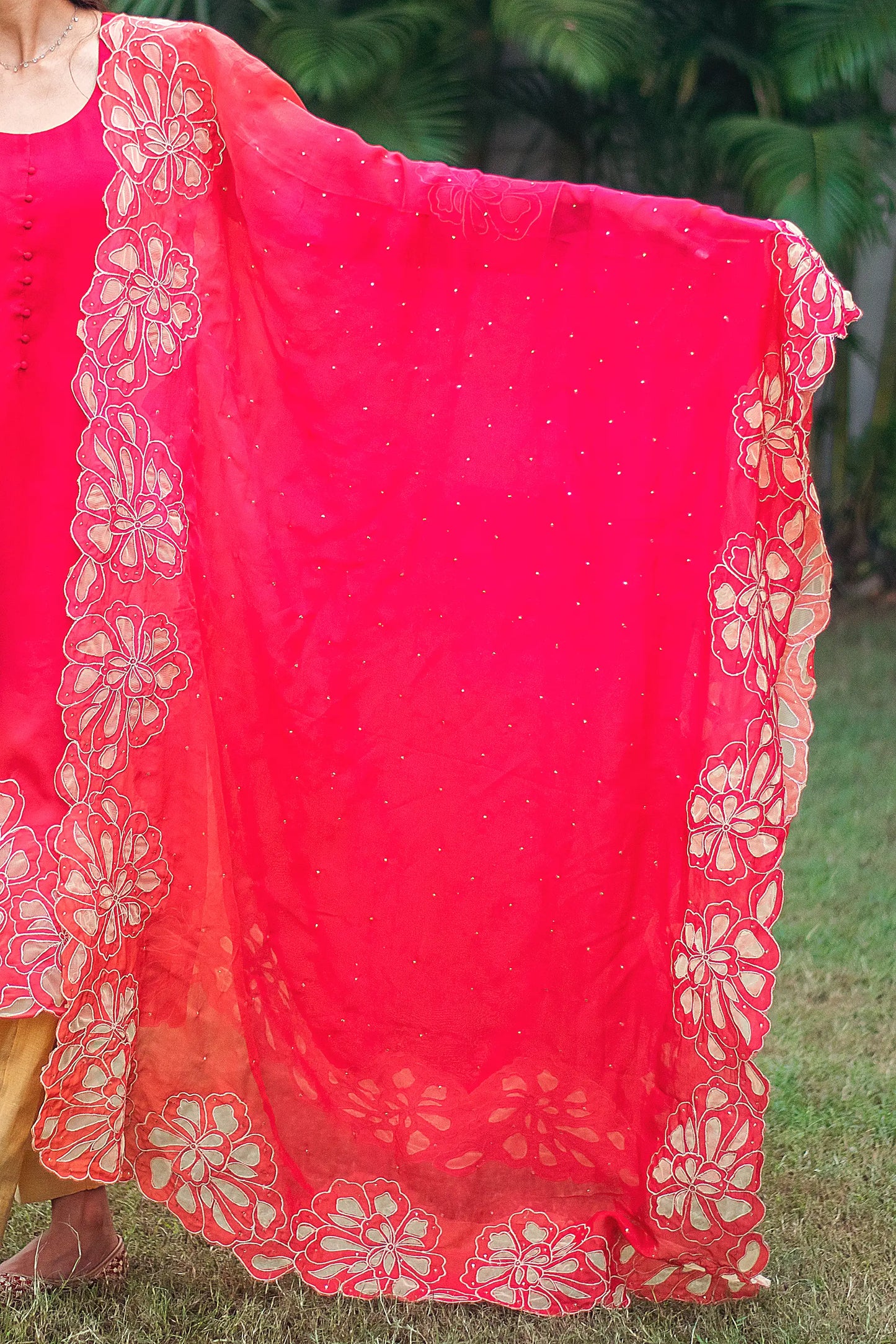 Indian model showing a red organza dupatta with gold floral cutwork along the borders.