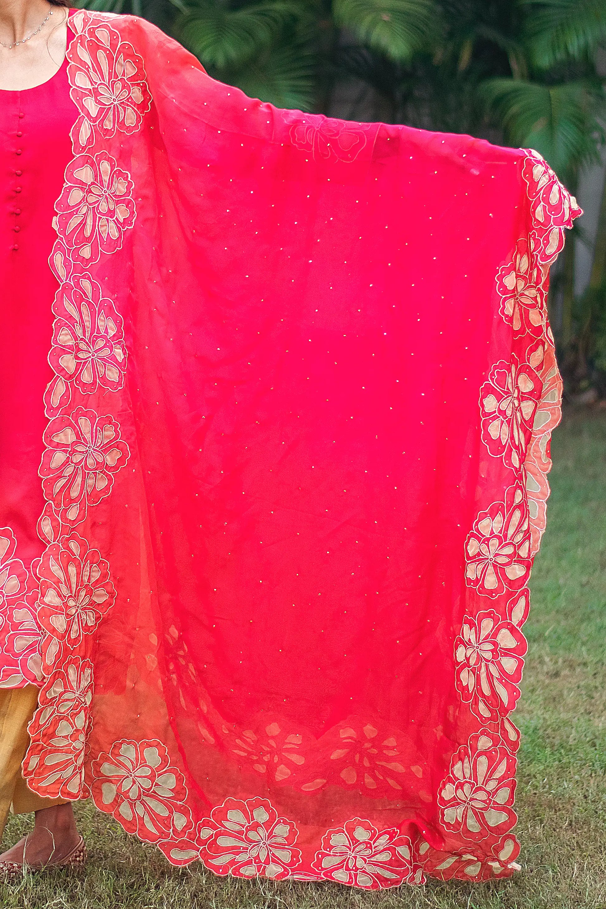 Indian model showing a red organza dupatta with gold floral cutwork along the borders.