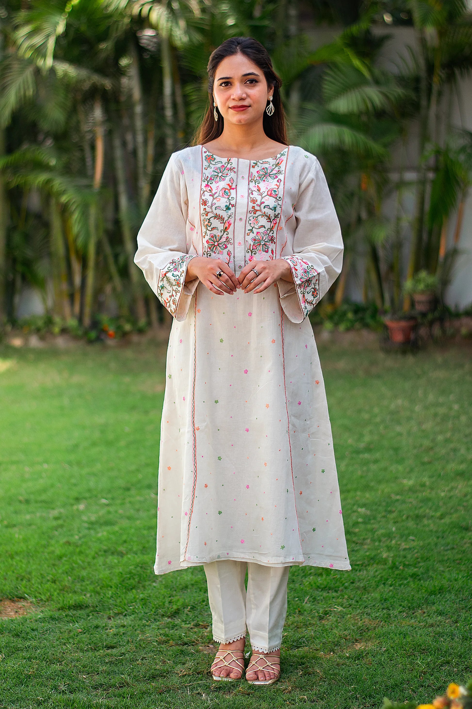 Indian model in an off-white kurta with Kashmiri embroidery and matching off-white trousers.