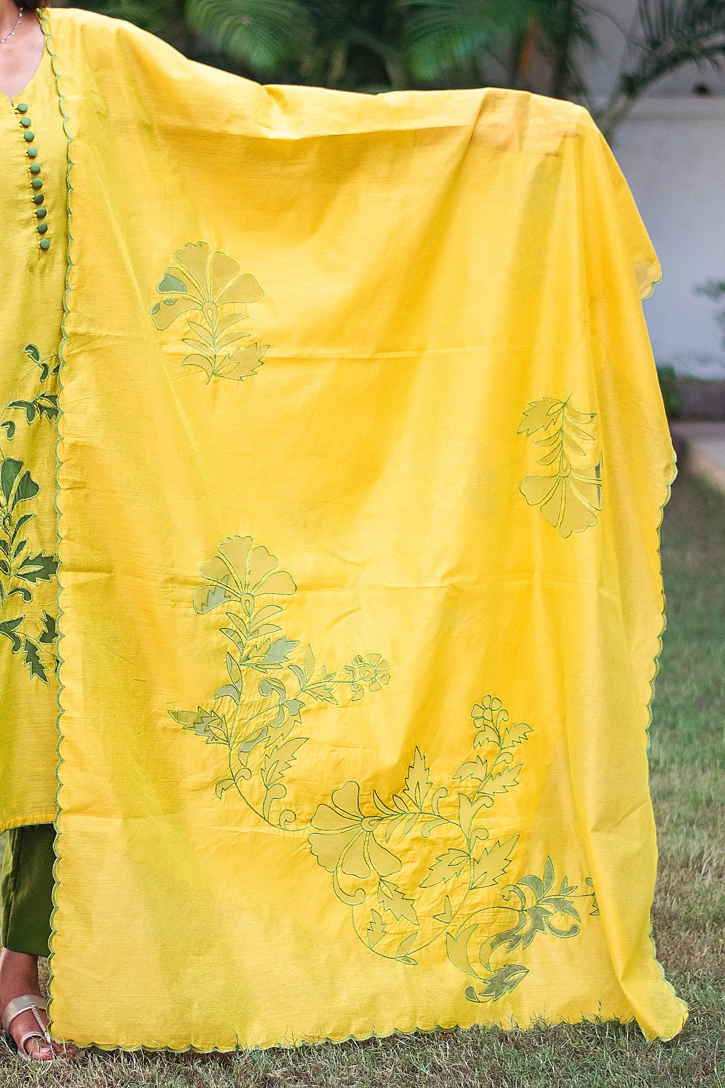 Detail of the green chanderi dupatta embellished with floral cutwork design in the form of a blooming vine, as styled by the model