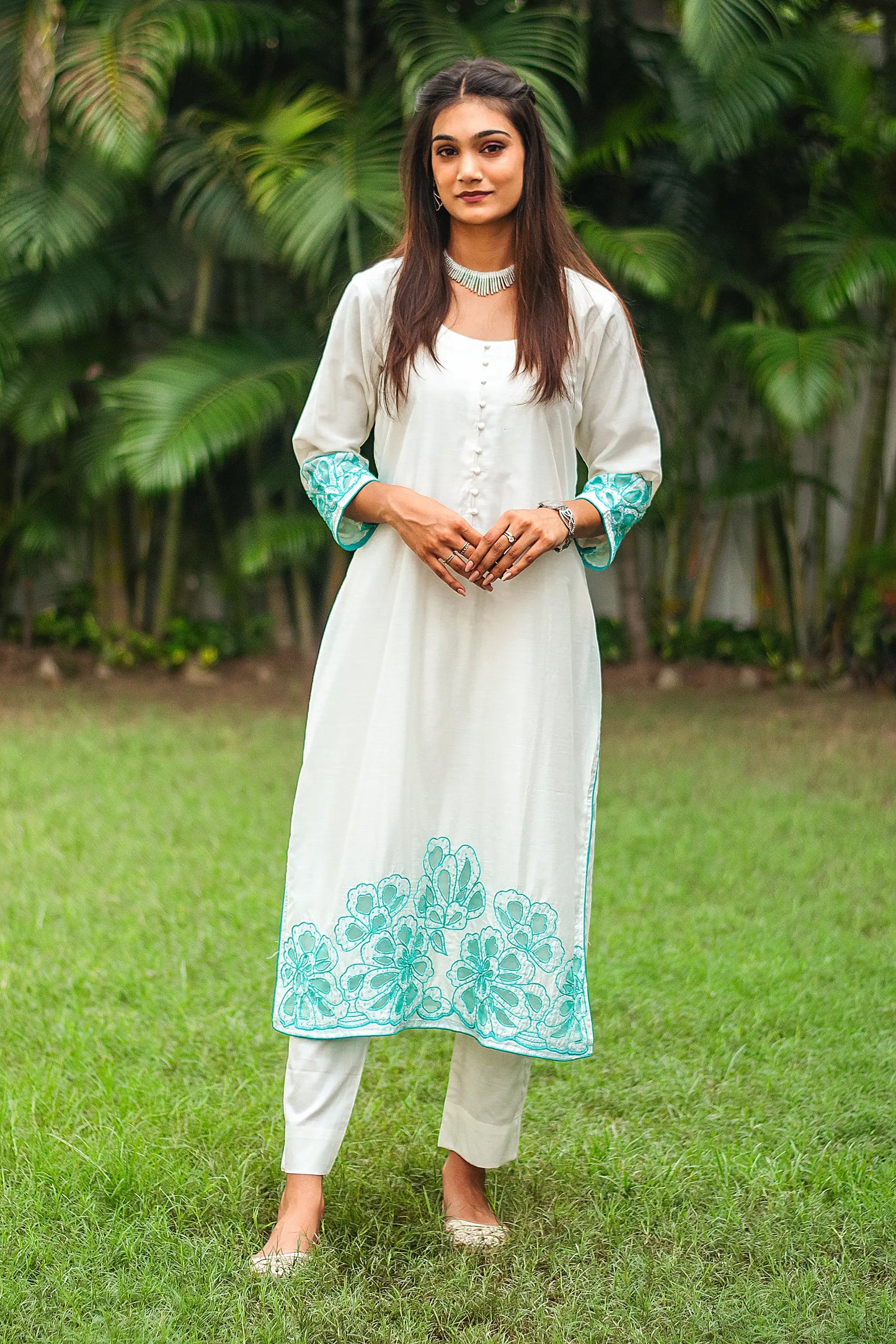 Front view of a model wearing the off-white Chanderi suit with cyan green floral cutwork, complete with off-white Chanderi kurta, cotton silk trousers