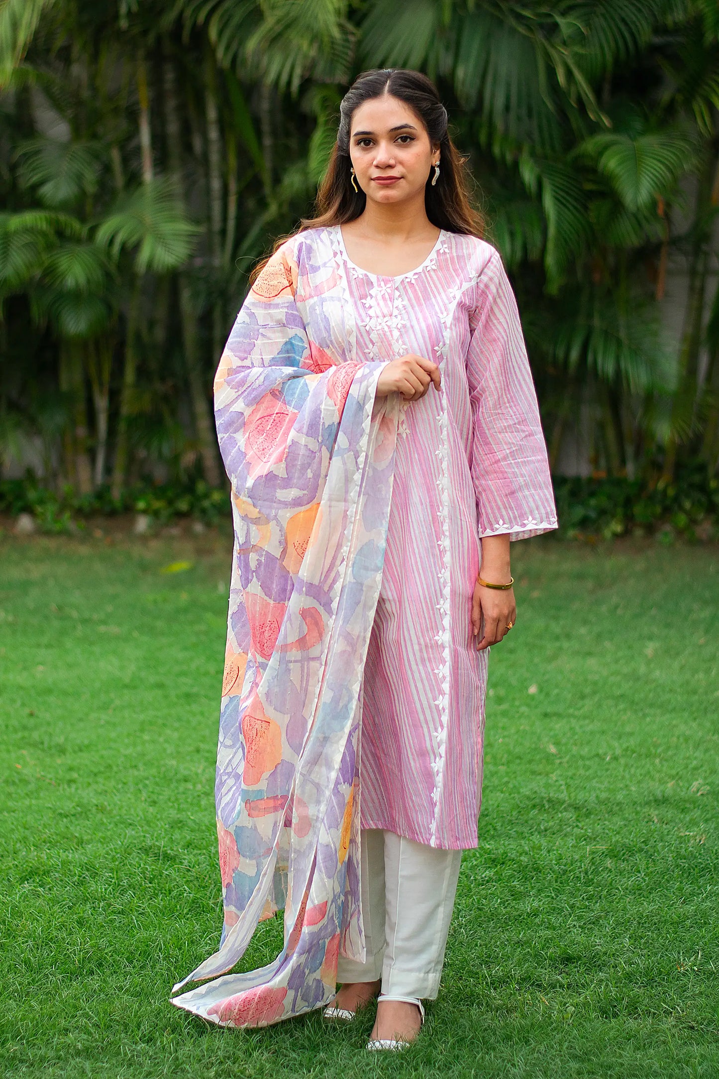  Indian model in a light pink kurta with applique work and matching pastel dupatta, paired with white trousers. 