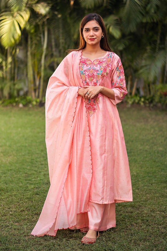 1. Indian model in a peach Chanderi A-line kurta with multicoloured resham embroidery, paired with a matching dupatta and palazzo.