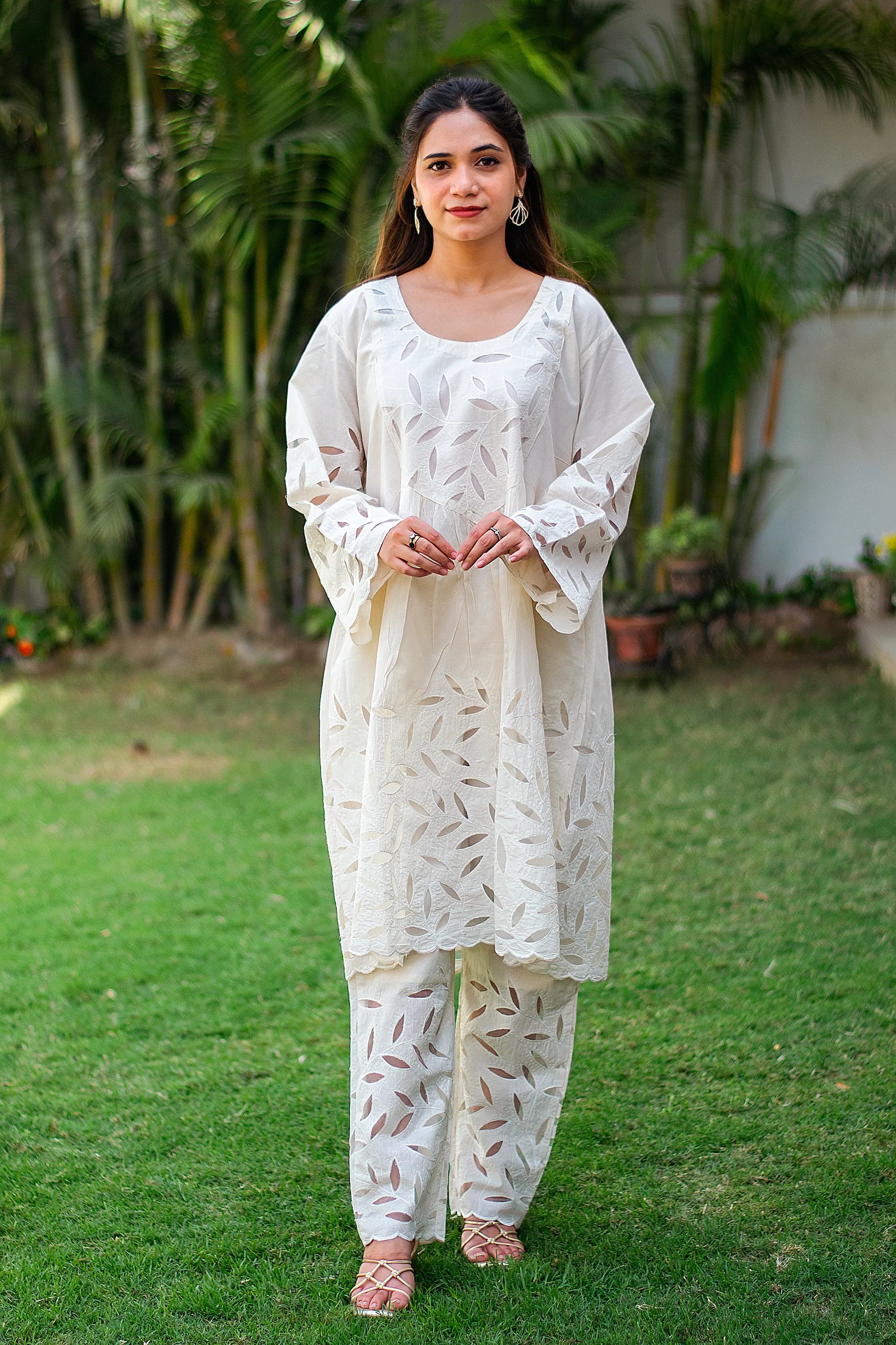 Indian model in an off-white embroidered kurta and matching pants with floral cutwork.