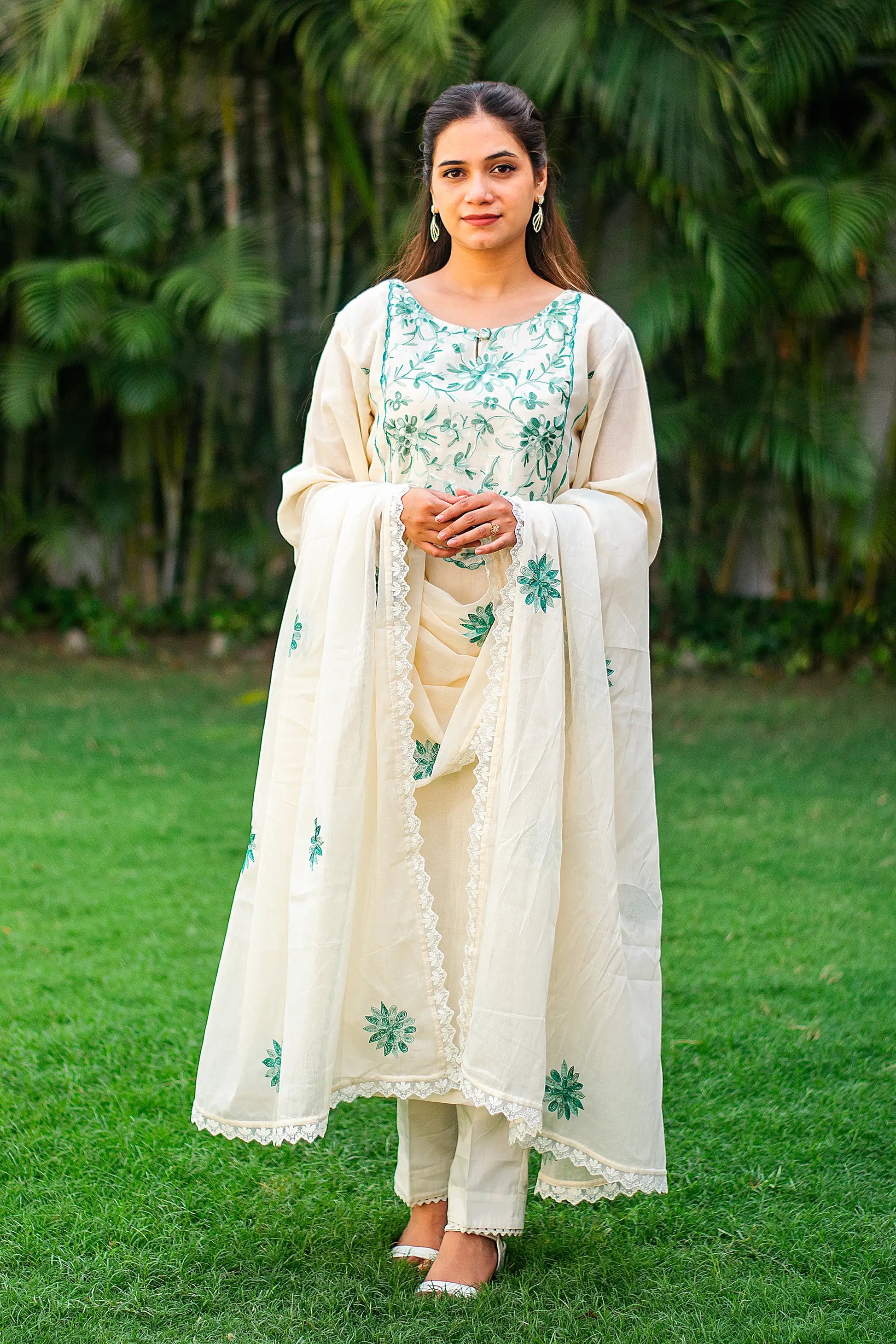 Indian model in an off-white kalidar kurti with green Kashmiri embroidery, paired with matching trousers and dupatta. 