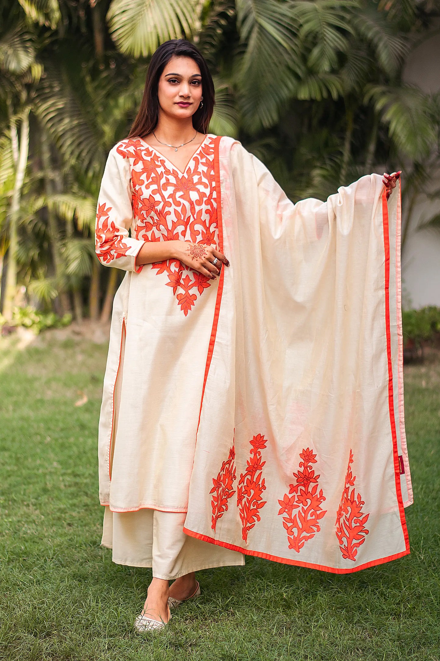 Indian model in a beige chanderi kurta and dupatta with orange floral patchwork, paired with a beige palazzo.