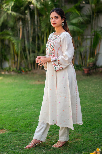 Side view of an Indian model in a kalidar style off-white kurta with Kashmiri embroidery, paired with off-white trousers. 