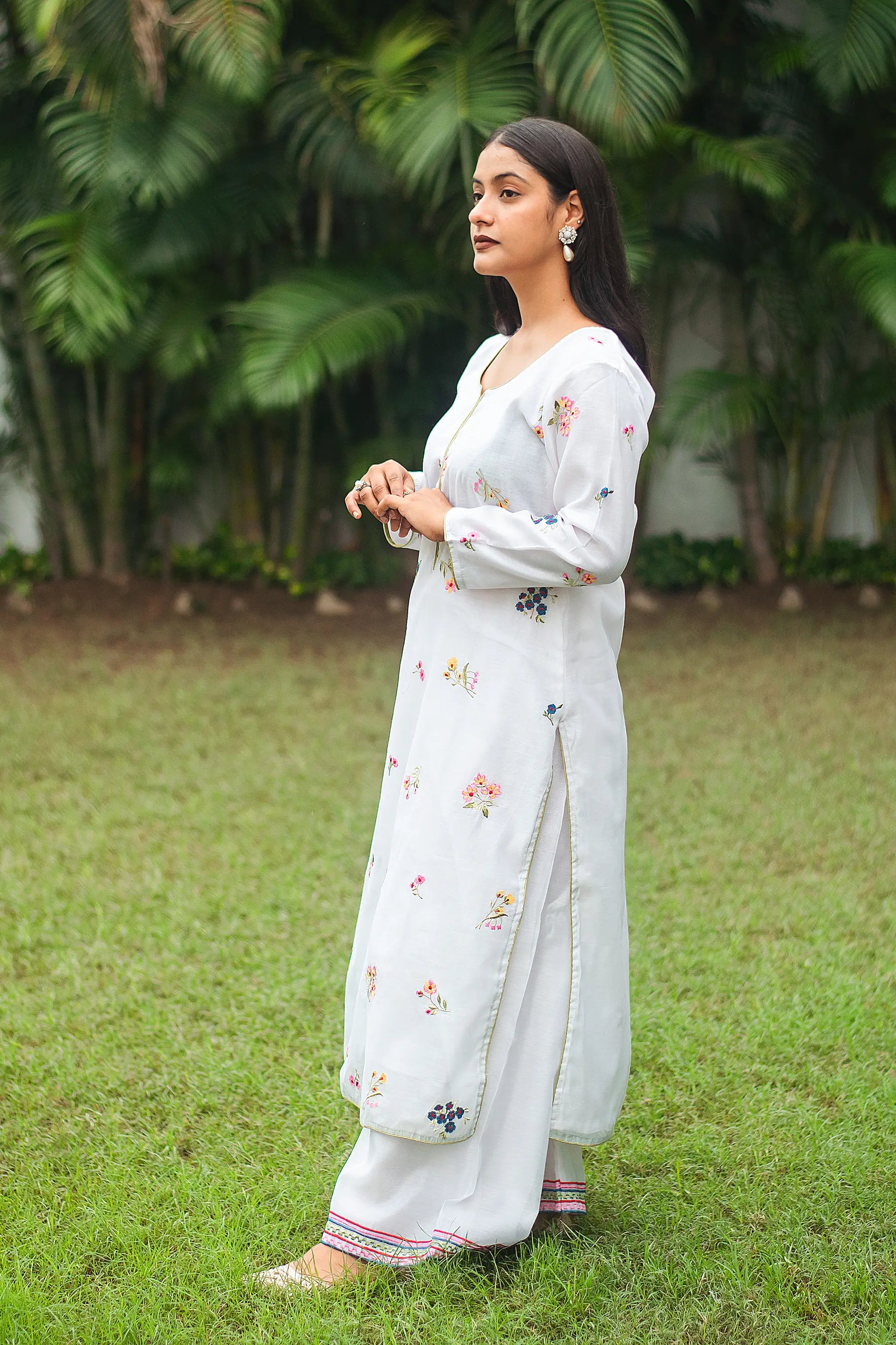 Side view of an Indian model in a white chanderi kurta with resham embroidery and white embroidered palazzo