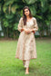 An indian woman wearing a printed staple tussar gold A line kurta and trousers. The woman looks in the camera