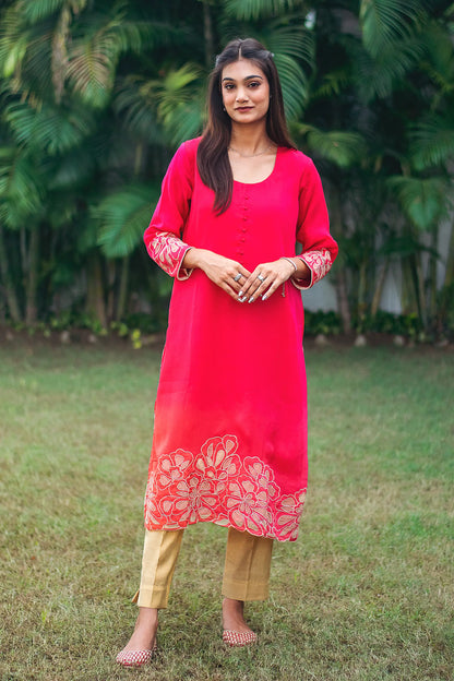 Indian model in a red organza kurta with gold floral cutwork, along the hem and cuffs, paired with gold brocade trousers.