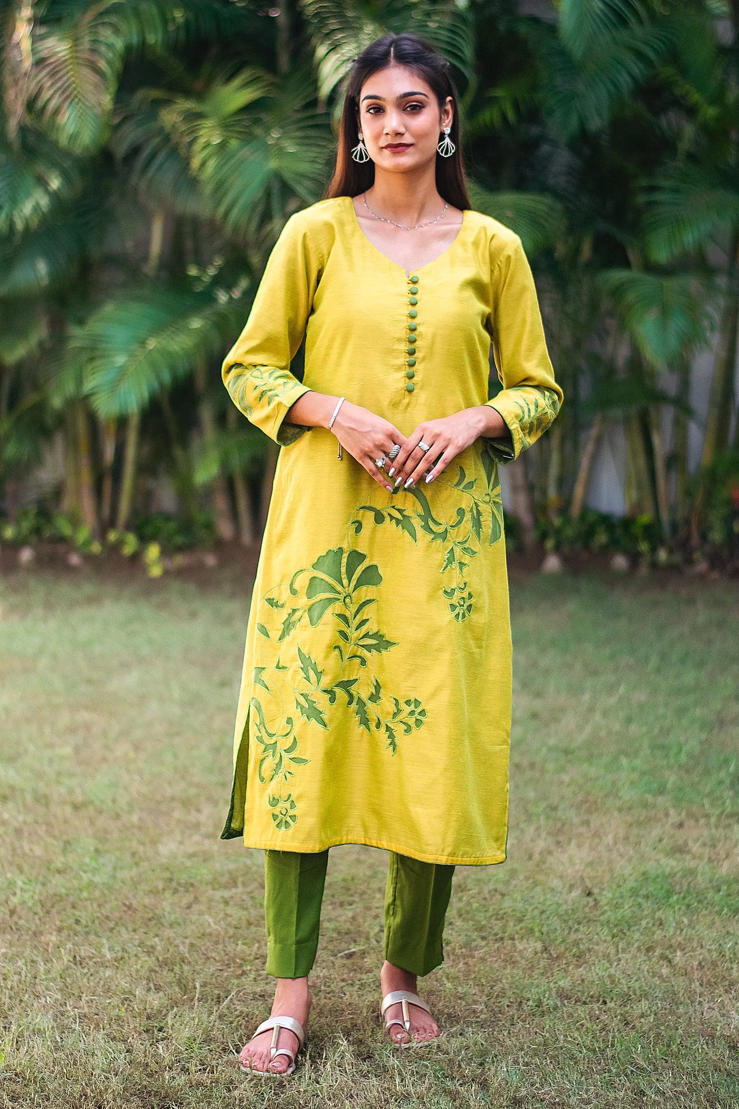 Front view of a model wearing the cutwork kurta set, featuring a yellowish-green chanderi kurta with green floral cutwork and drak green  trousers