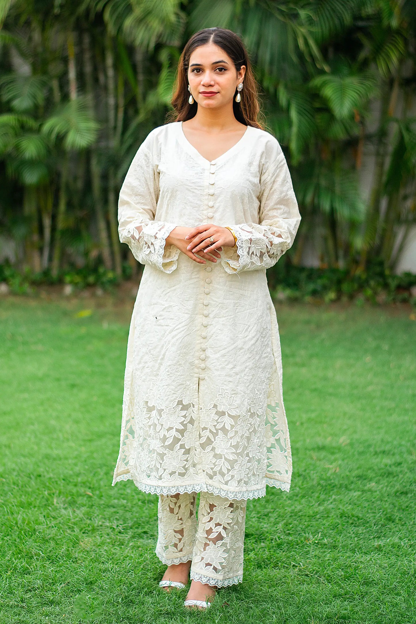 Indian model wearing a white cotton kurta and matching trousers  adorned with cutwork.