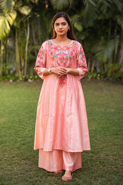 Indian model in a peach Chanderi kurta with multicoloured resham embroidery and pink sequins, paired with matching peach palazzo.