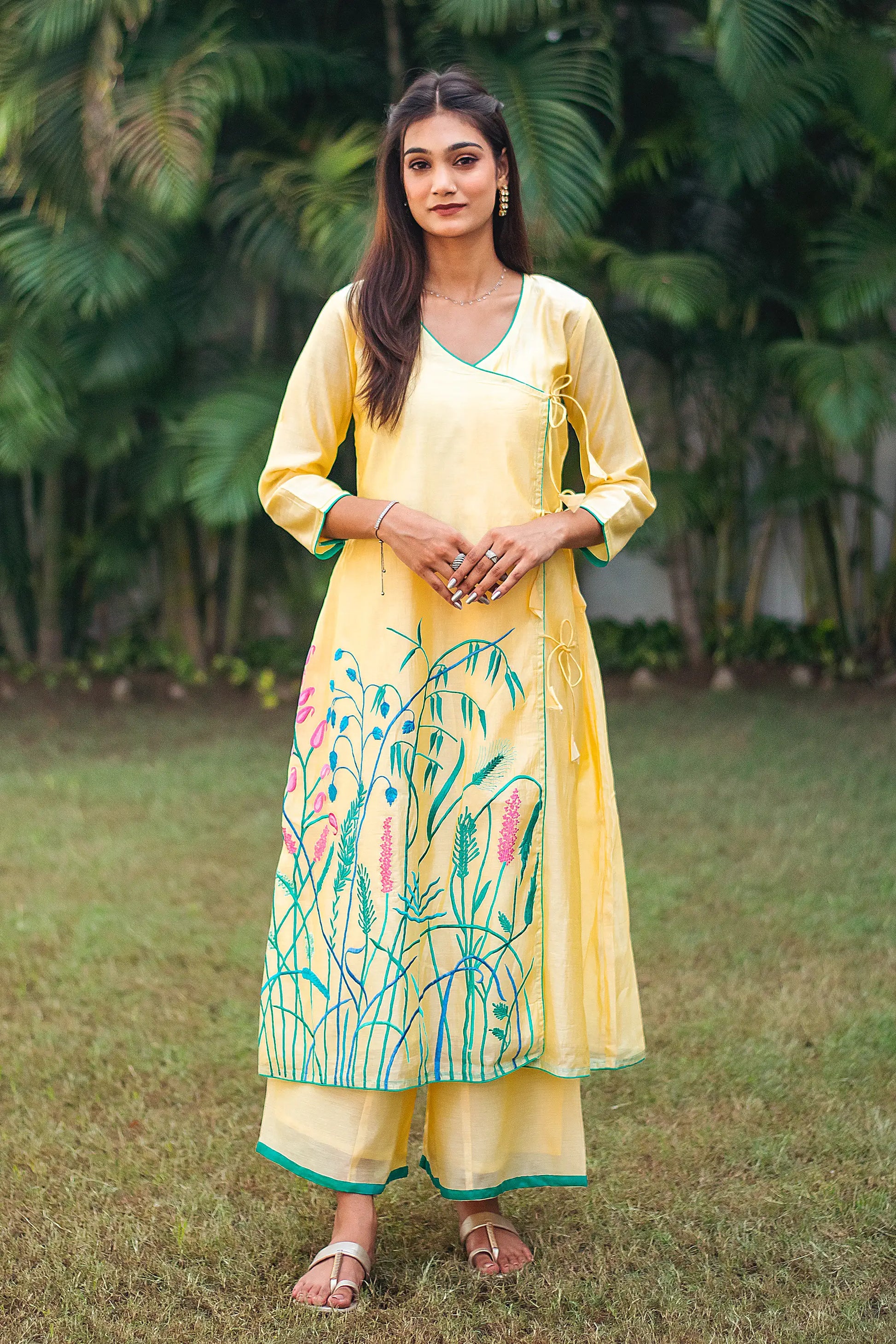 Indian model in a yellow angrakha kurta with pink and teal floral resham embroidery, paired with matching palazzo.