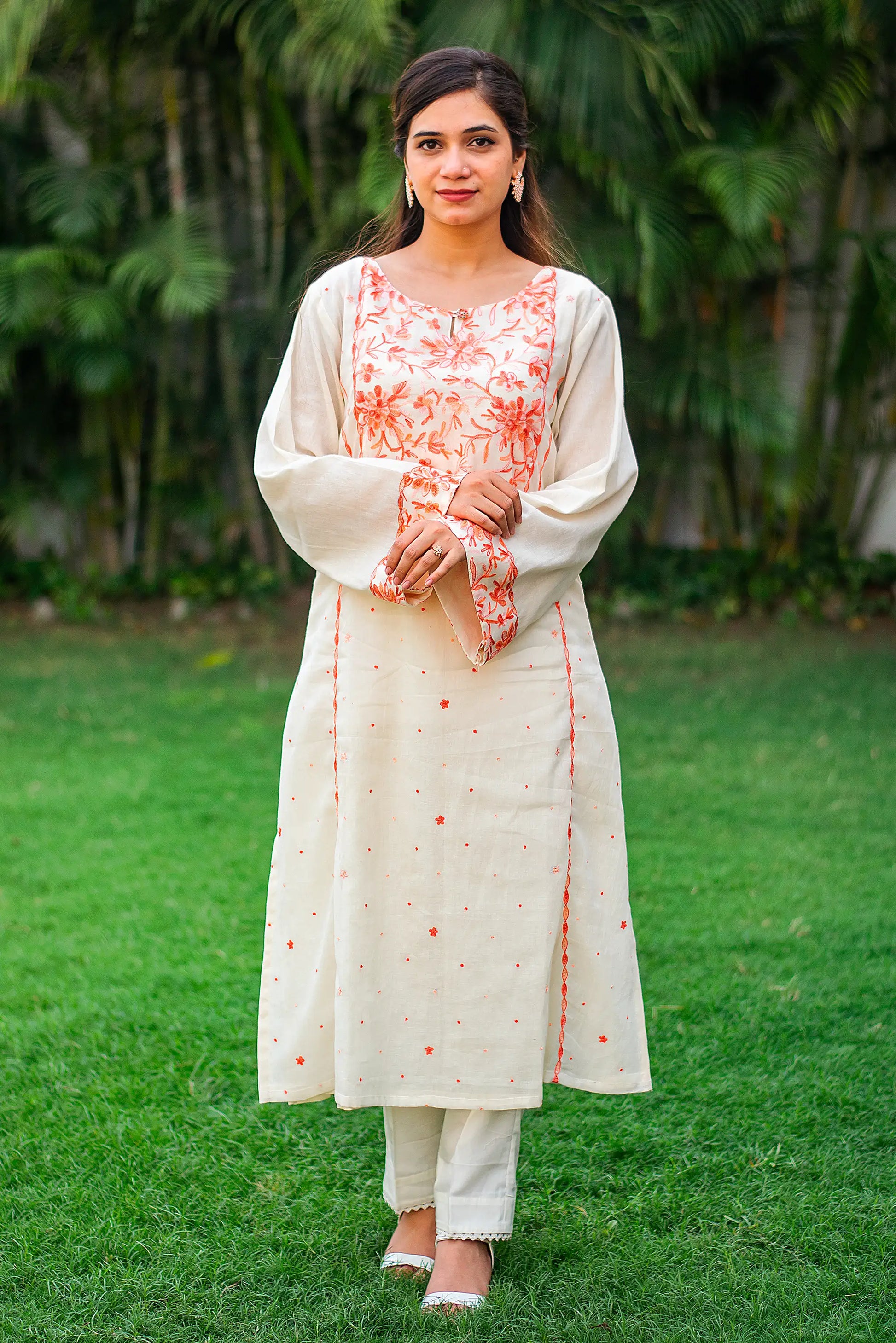 Indian model in an off-white kurta with peach Kashmiri embroidery and matching off-white trousers.