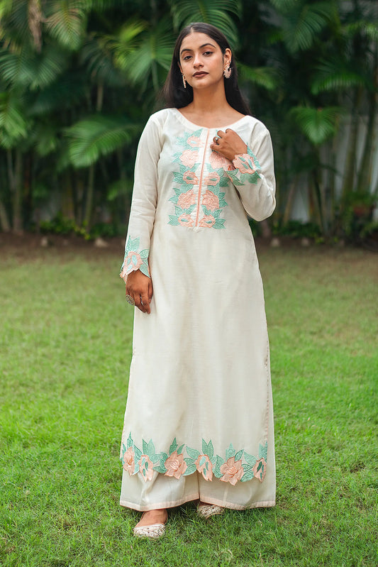 Indian model in a cream chanderi kurta with peach floral patchwork, paired with cream palazzo.