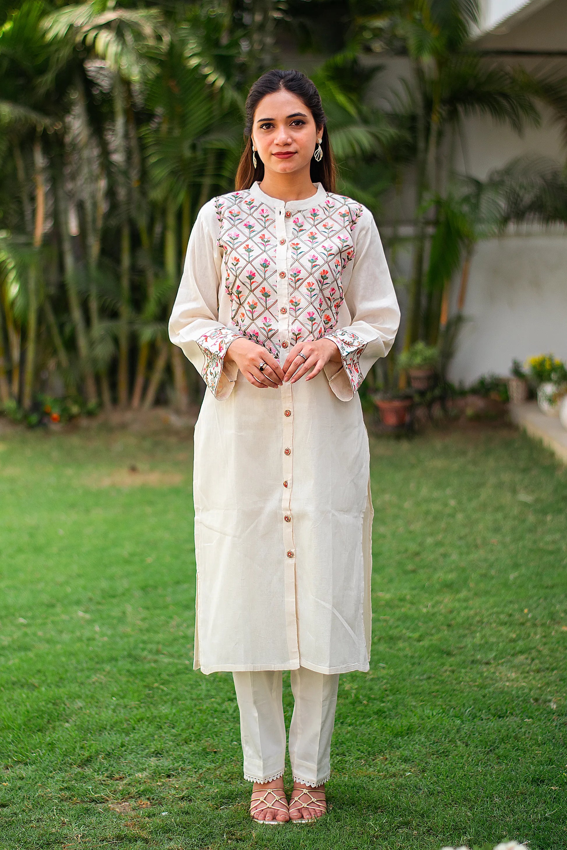 Indian girl in an off-white front-open cotton kurti with floral Kashmiri embroidery, styled with a matching trousers.