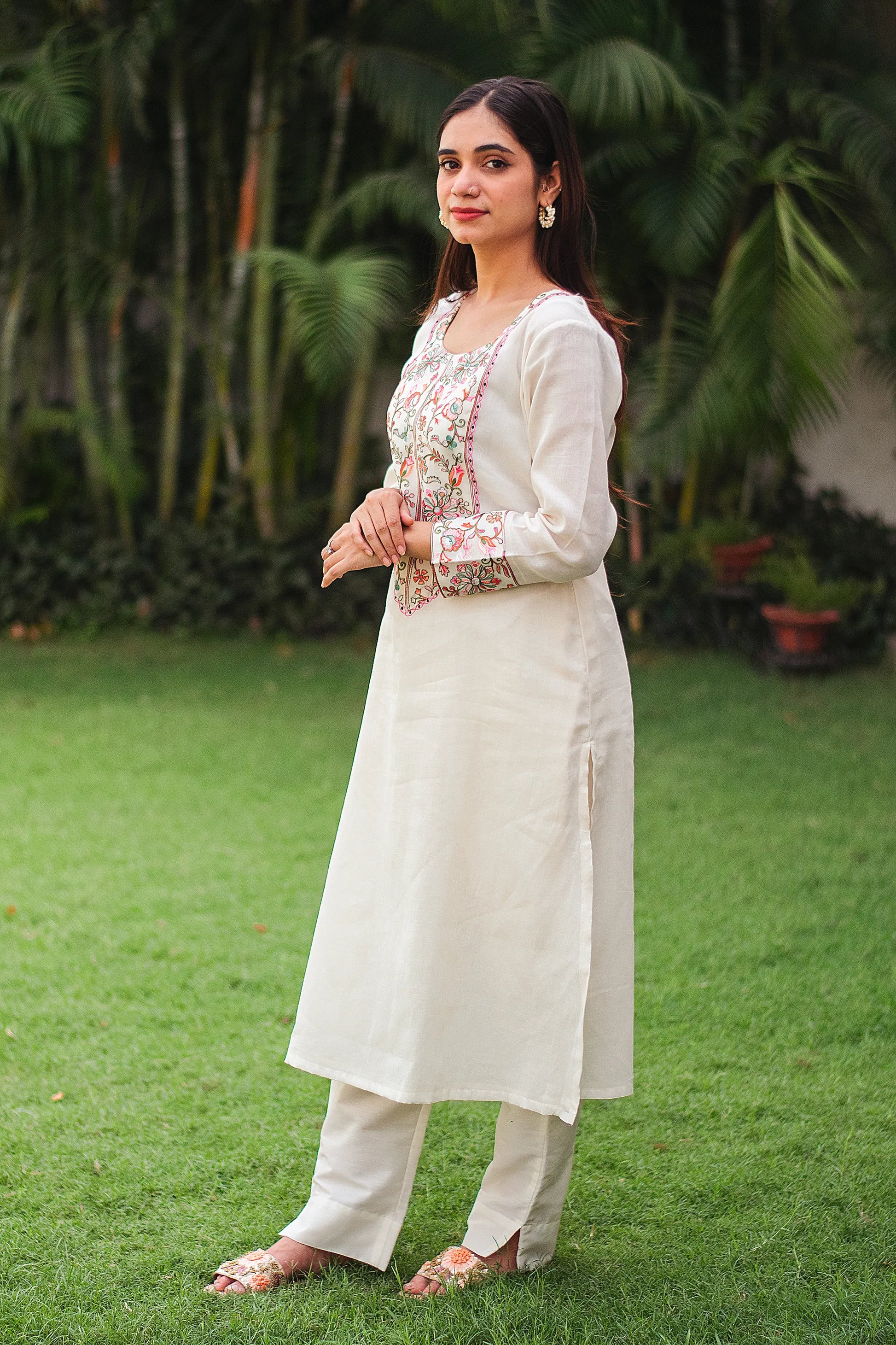 Indian model in a side view showcasing an off-white Kashmiri embroidered kurta and trousers, without the dupatta