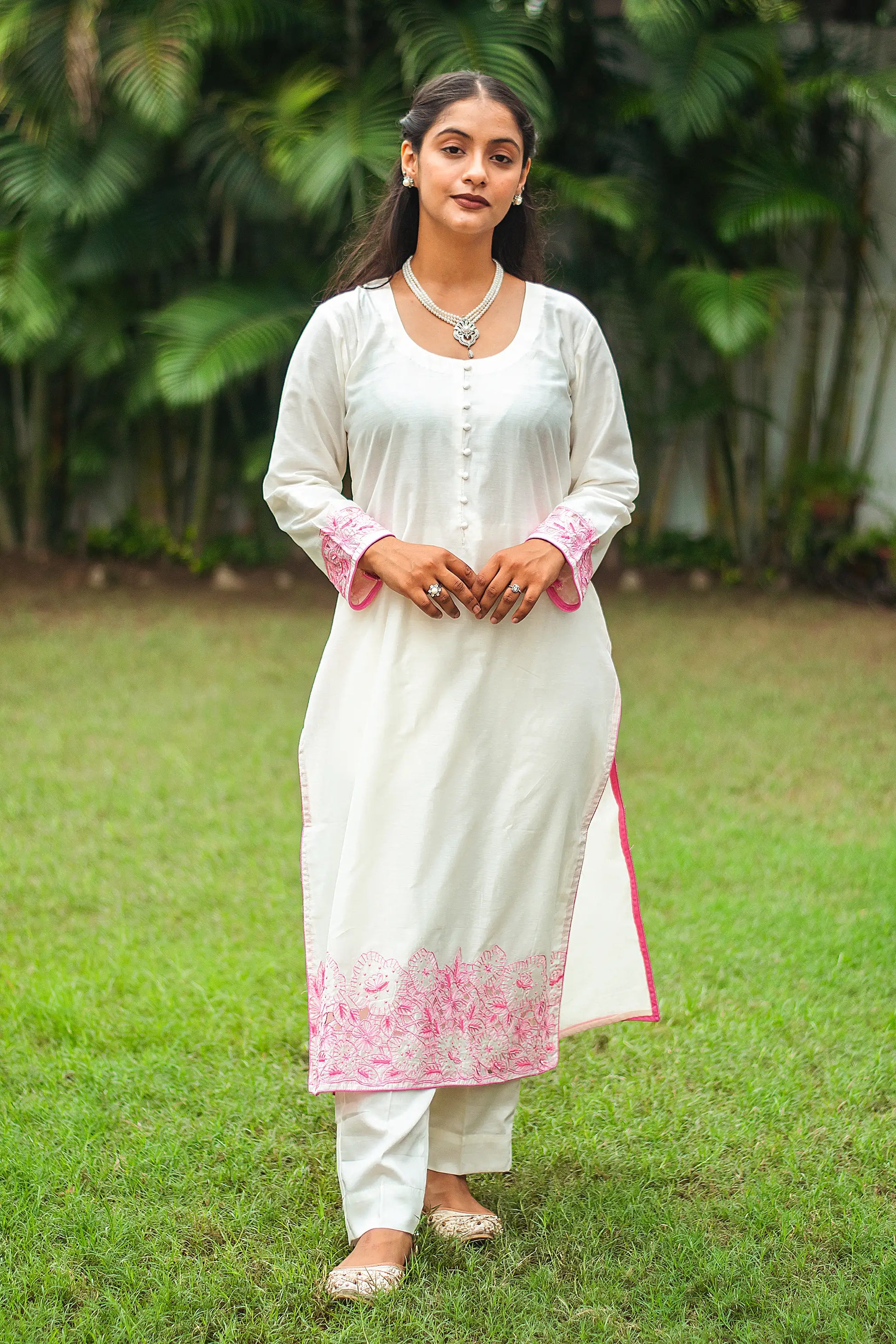 Indian model in an off-white chanderi kurta with pink floral cutwork and sequins, paired with off-white trousers.