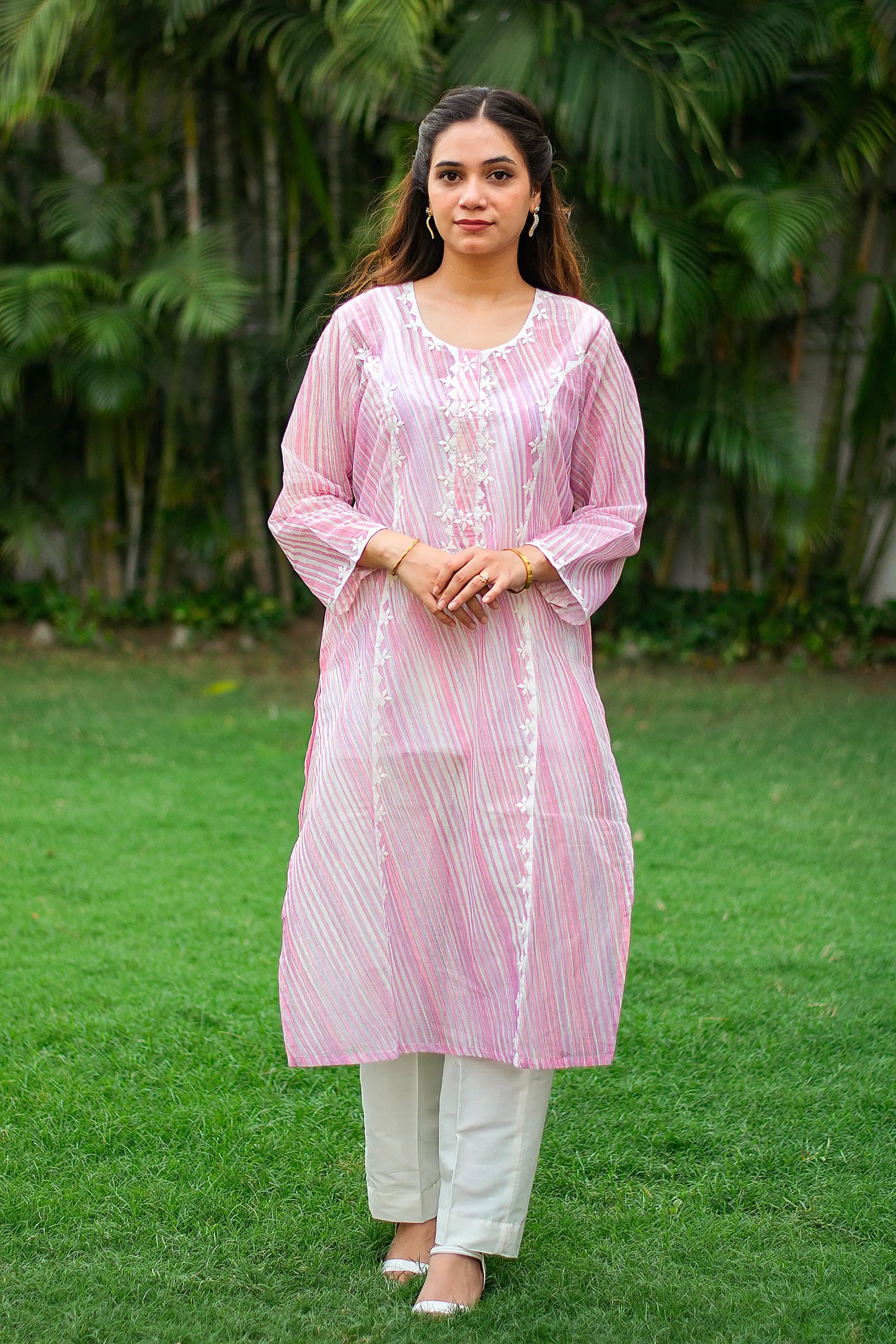 Indian model in a light pink leheriya print kurta with applique work and white trousers.