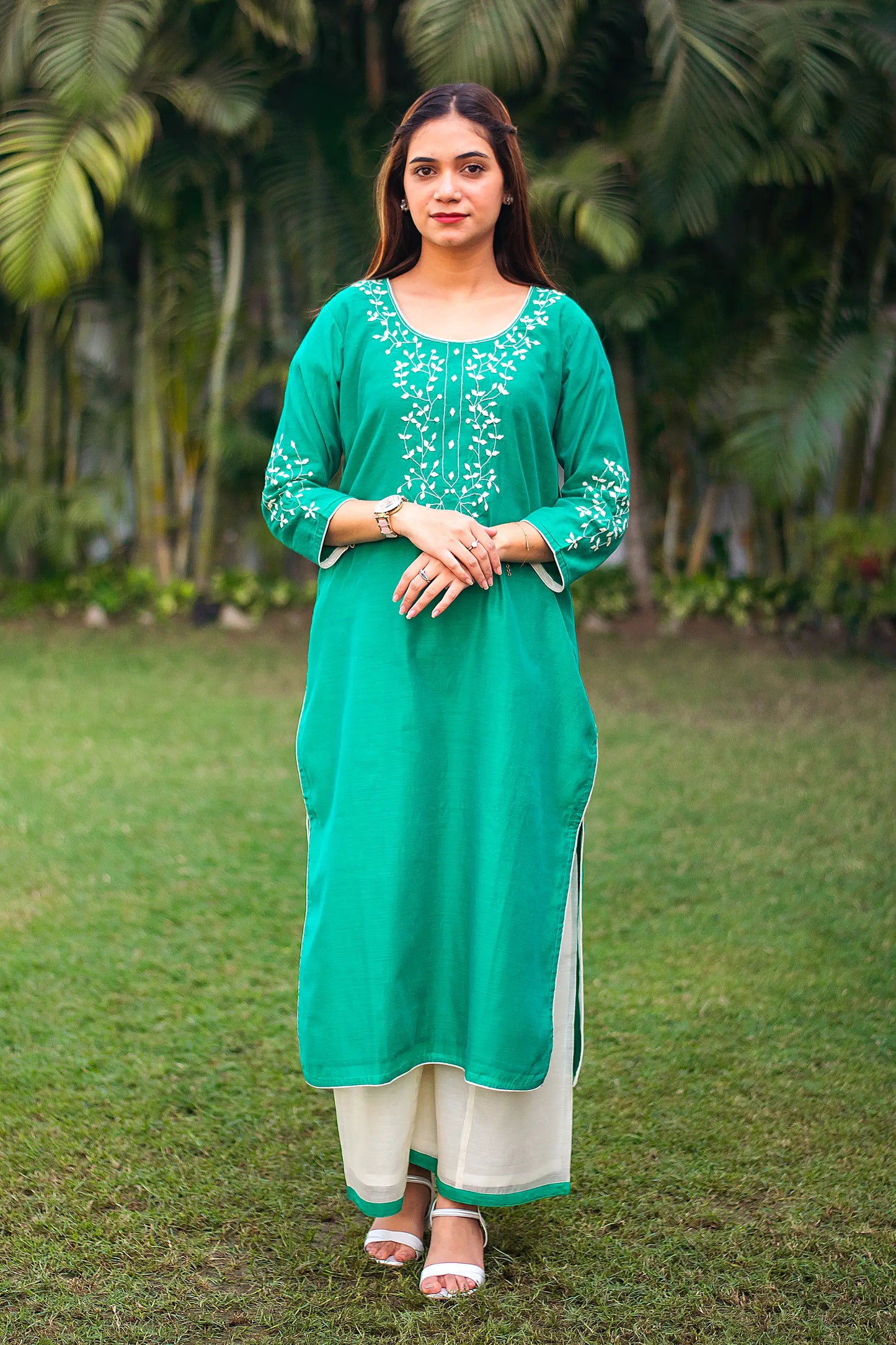 An Indian girl wearing a green Chanderi kurta with applique work and white palazzo, full length is visible.