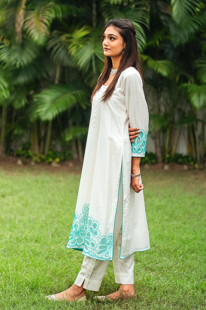 Left side view of a model wearing the off-white Chanderi suit with cyan green floral cutwork, highlighting the suit's elegant silhouette