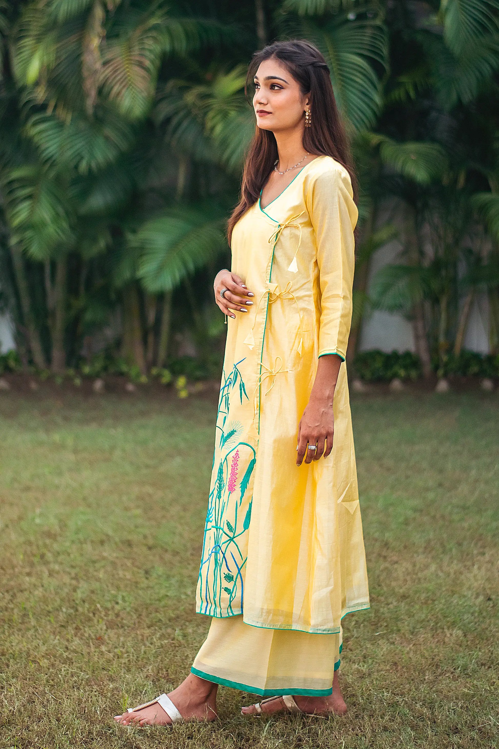 Side view of an Indian model in a yellow angrakha kurta with floral resham embroidery, paired with matching palazzo.