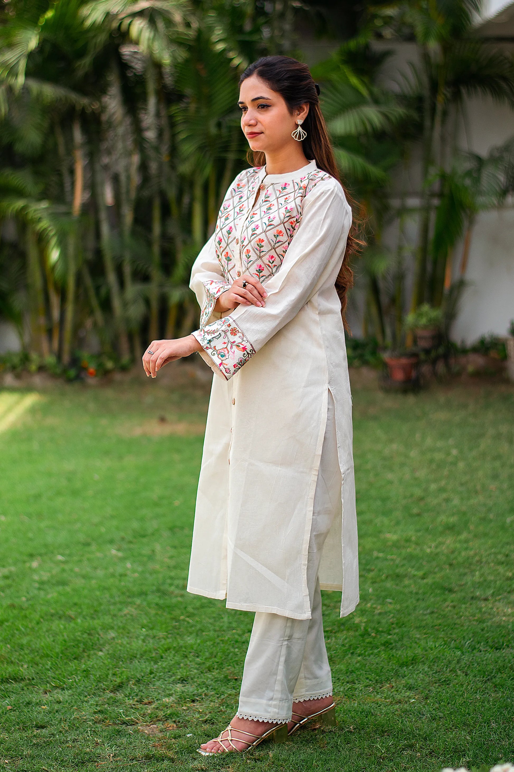 Indian girl in side pose wearing an off-white front-open cotton kurti with Kashmiri embroidery, paired with matching trousers.