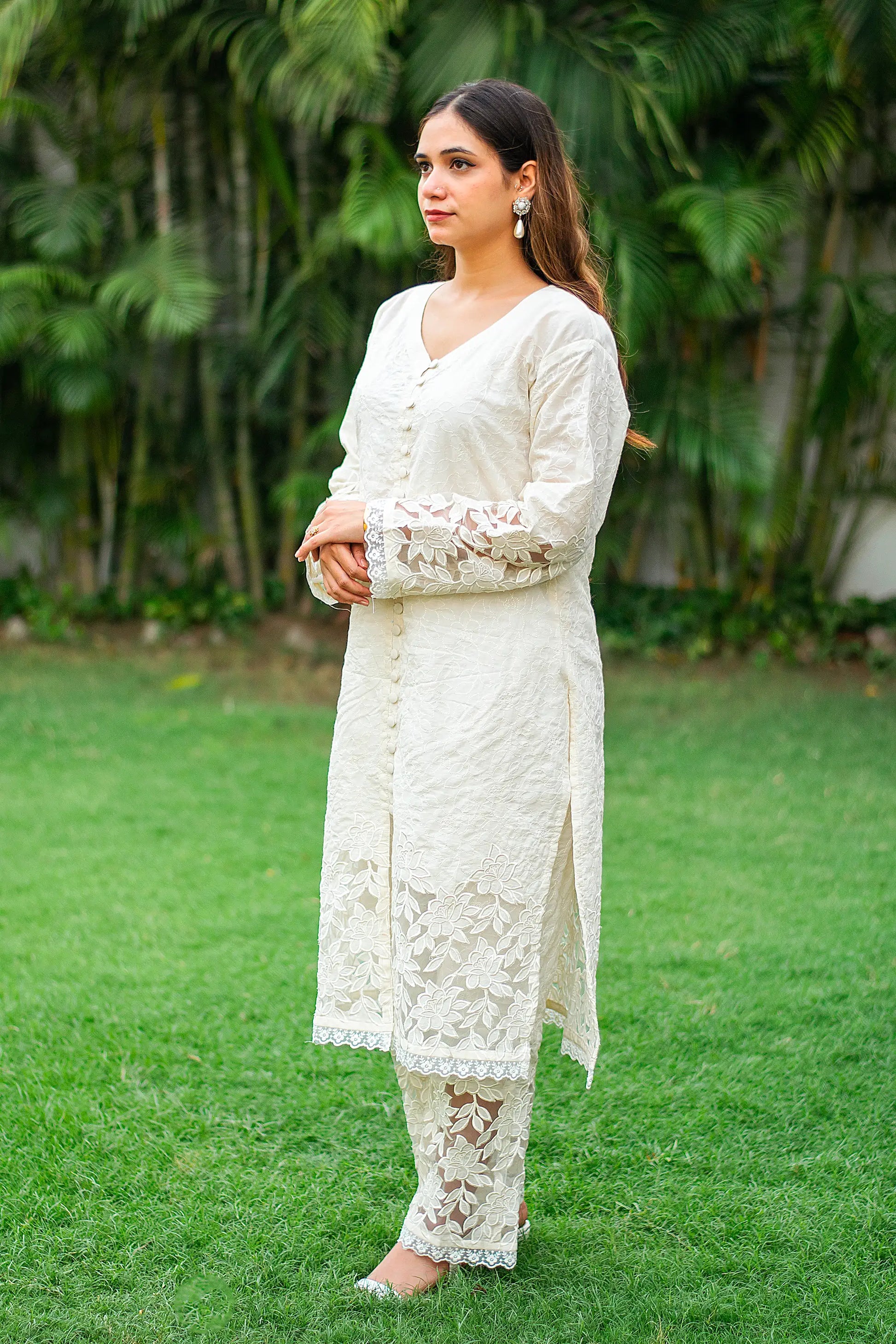 Side view of an Indian model in a white front-open kurta with floral cutwork, paired with matching trousers. 