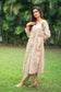 An indian woman wearing a printed staple tussar gold A line kurta and trousers with gold chanderi dupatta. The A line kurta has double kali in red colour. The woman is showcasing the attire sideways and the entire ensemble is visible.