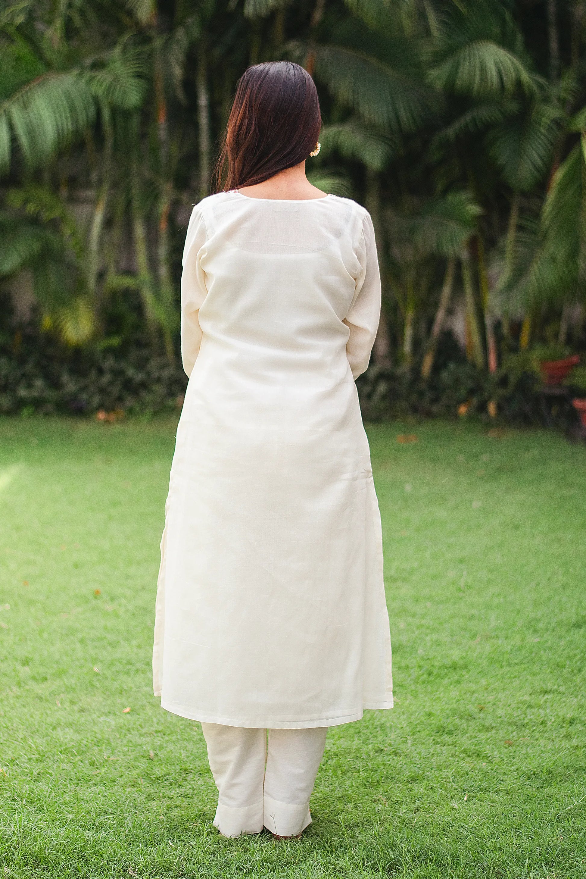 Indian girl in an off-white cotton kurta set with a plain back, facing away