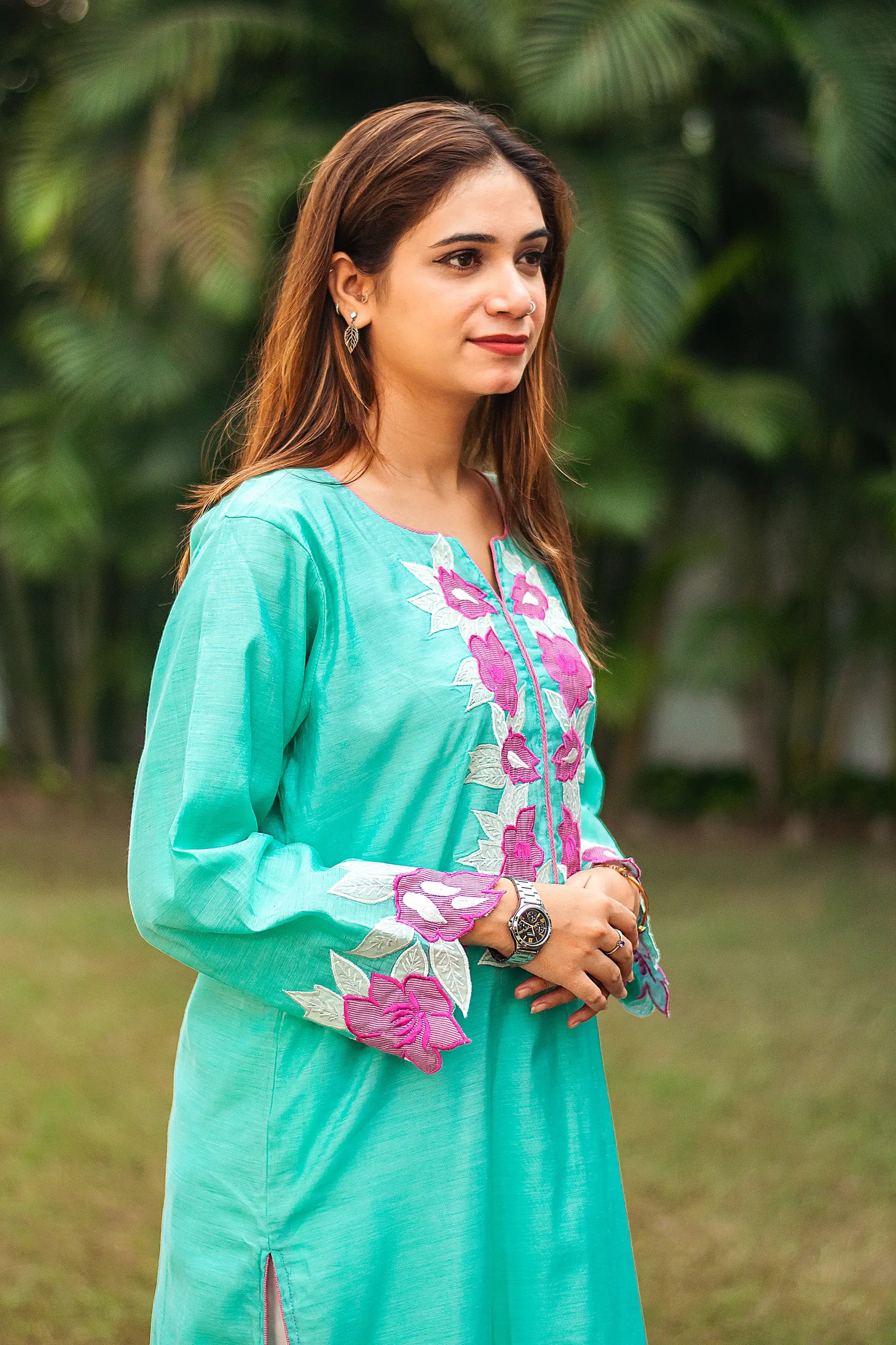 Side view of an Indian model in a blue chanderi kurta with purple patchwork flowers on the hem and cuffs.