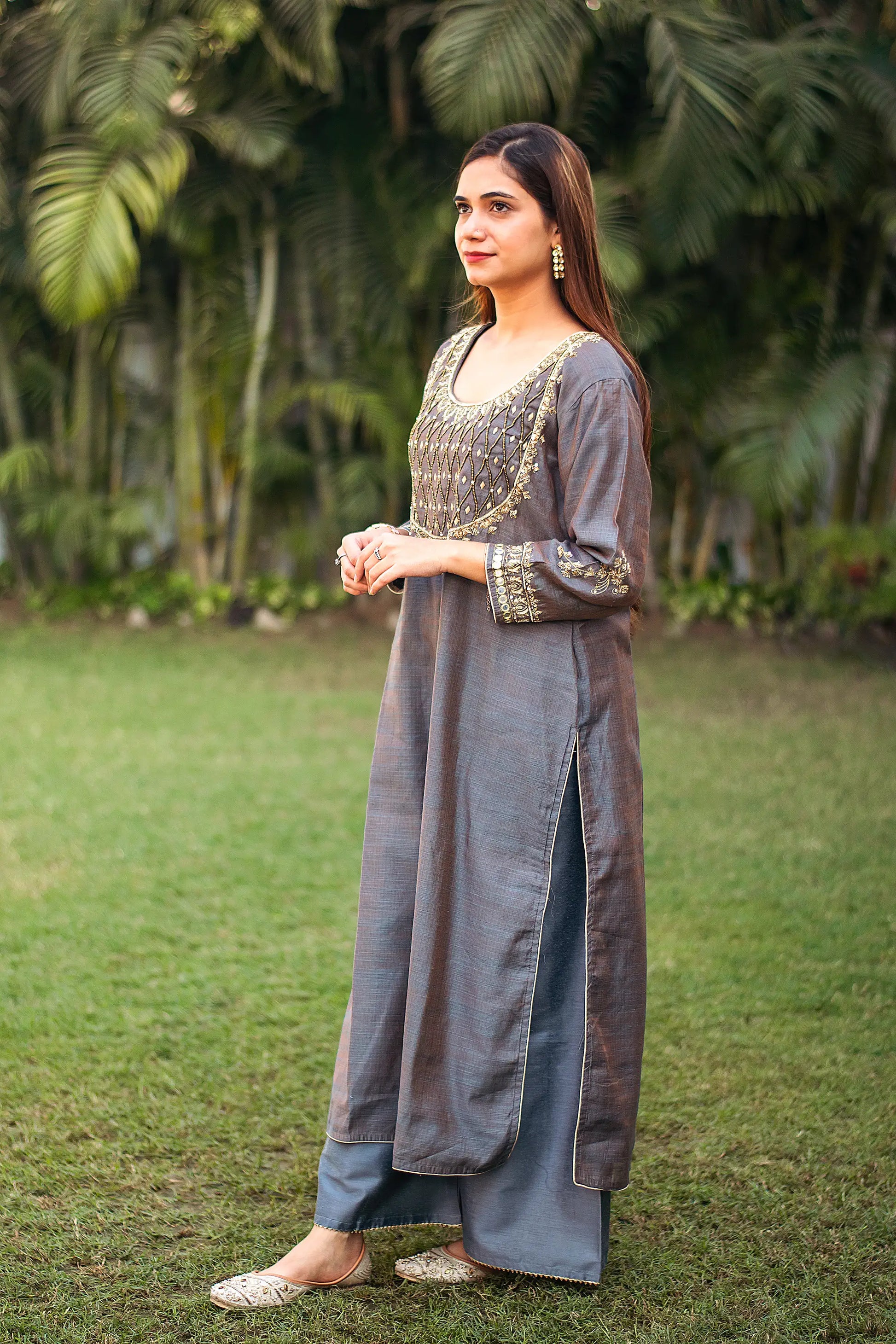 Side pose of an Indian woman in a grey silk kurta with zardozi work, paired with grey palazzo.