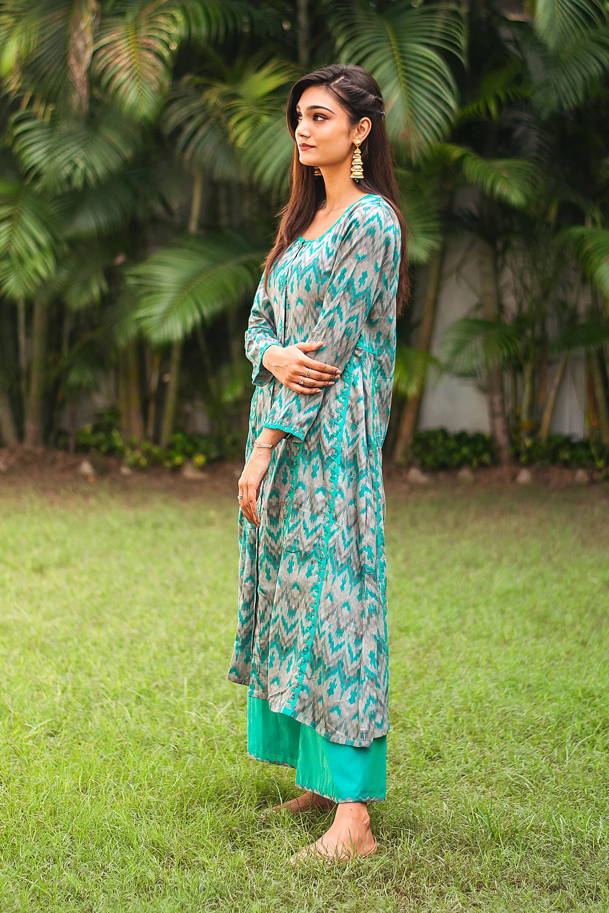 Side view of an Indian model in a green and grey ikat print kurta with green applique work, complemented by green palazzo.