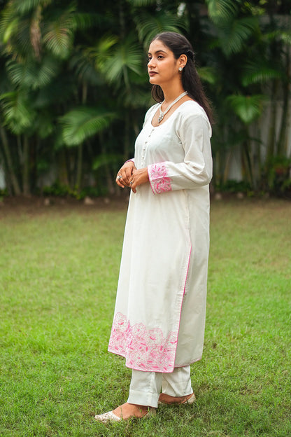 Side view of an Indian model in an off-white chanderi kurta with pink cutwork and sequins, paired with off-white trousers.