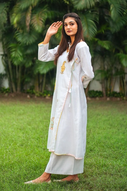 Side view of an Indian model in a white chanderi angarkha kurta with kairi patchwork, paired with white chanderi palazzo.