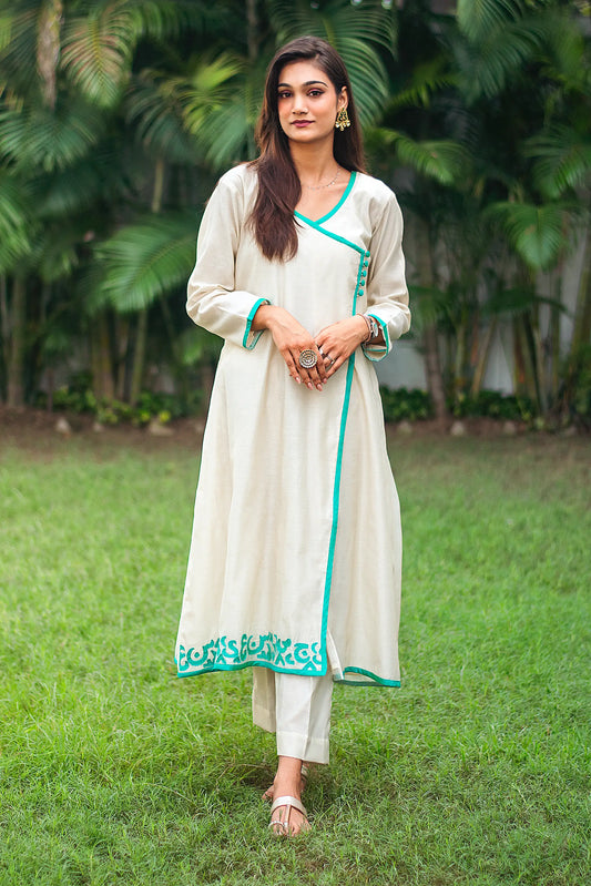 Front view of a model wearing the beige chanderi angrakha set, featuring a beige chanderi angrakha with green calligraphy patchwork, matching trousers