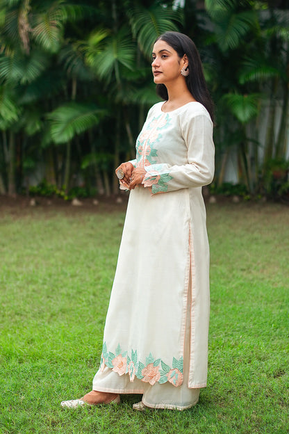 Side view of an Indian model wearing a cream chanderi kurta with peach patchwork, paired with matching cream palazzo.