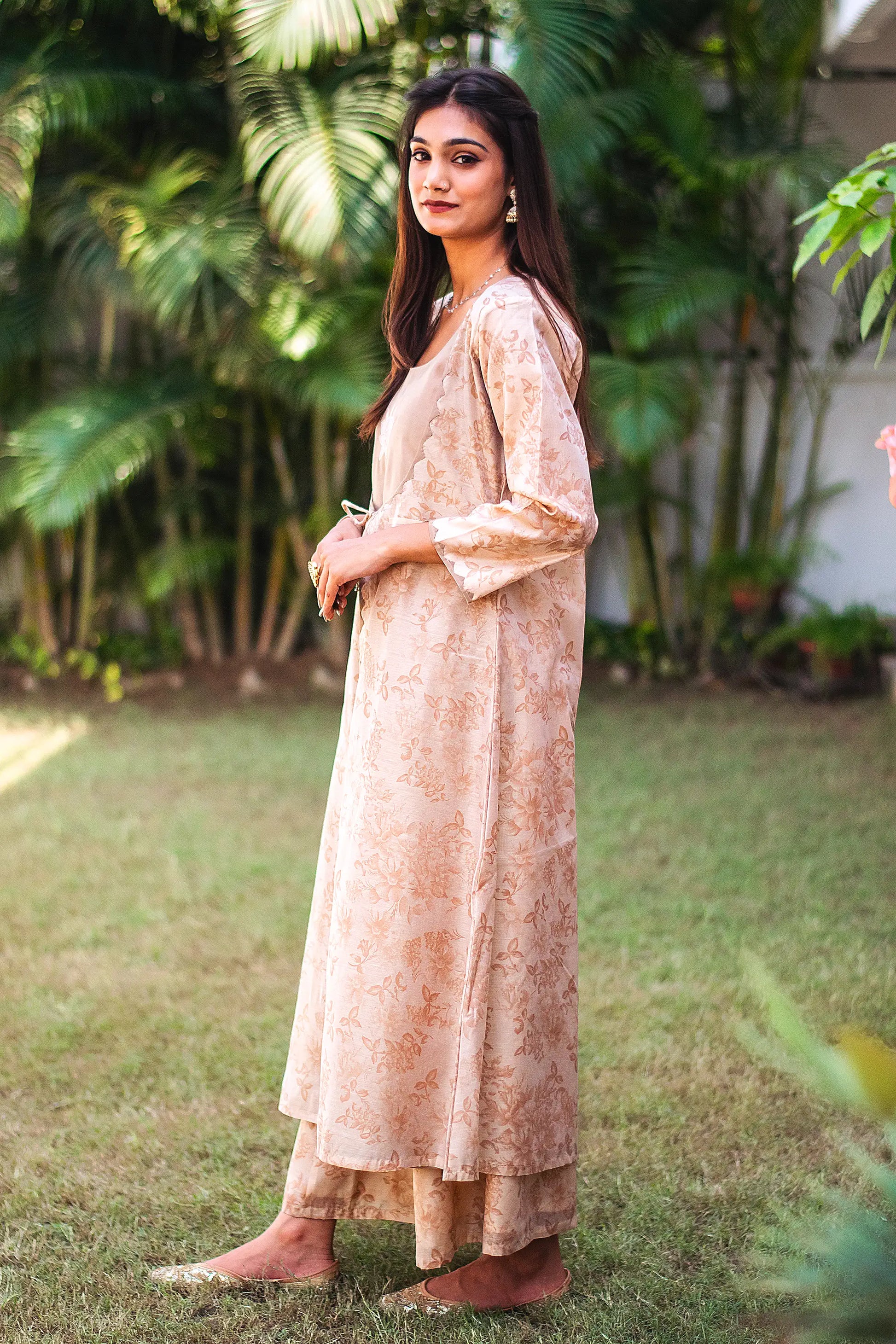 Left side view of a model wearing the beige floral print kurta set, highlighting the angrakha-style kurta's unique silhouette
