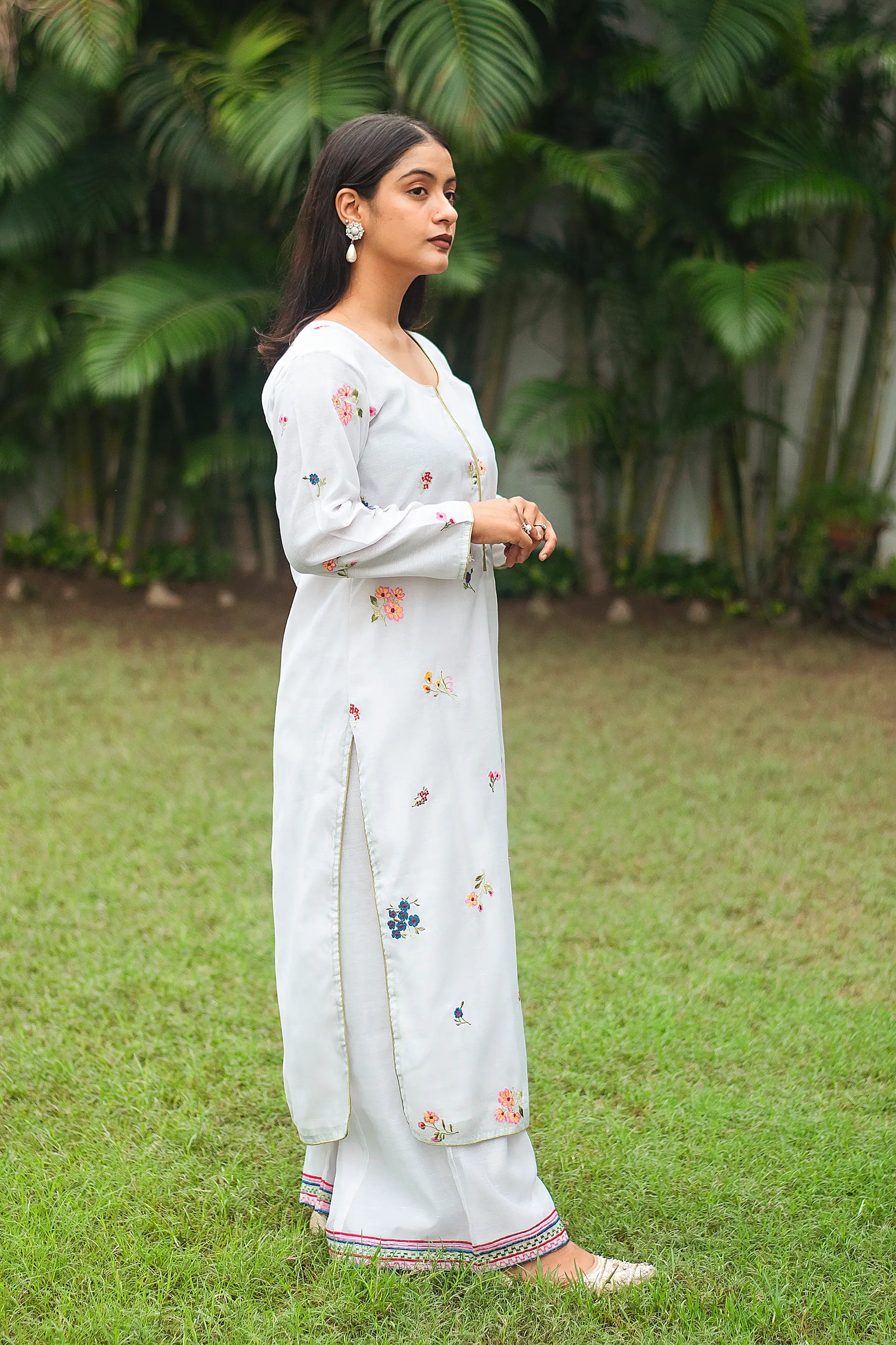 Indian model in a side pose wearing a white embroidered chanderi kurta and palazzo.