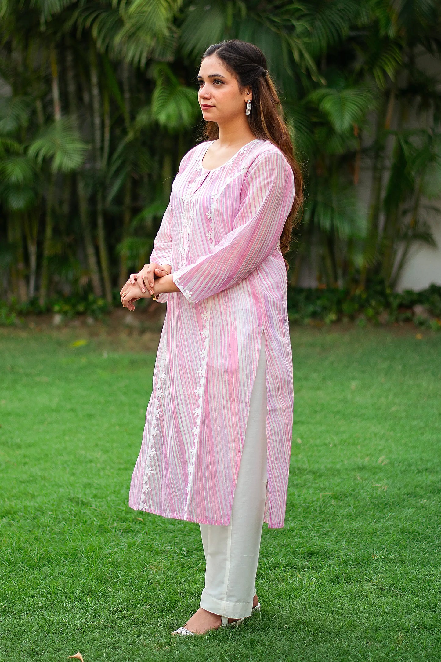 Side view of an Indian model in a pink kurta with applique work, paired with white trousers. 