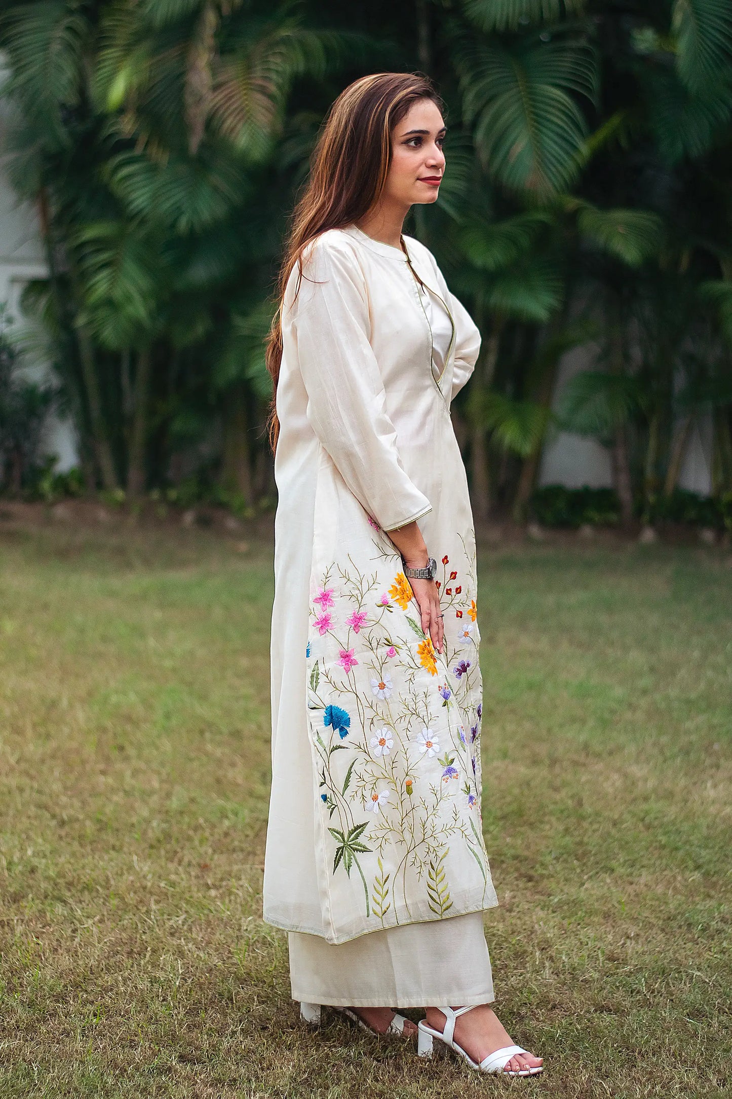 Side view of an Indian model in an off-white angrakha kurta with floral embroidery, paired with matching palazzo.