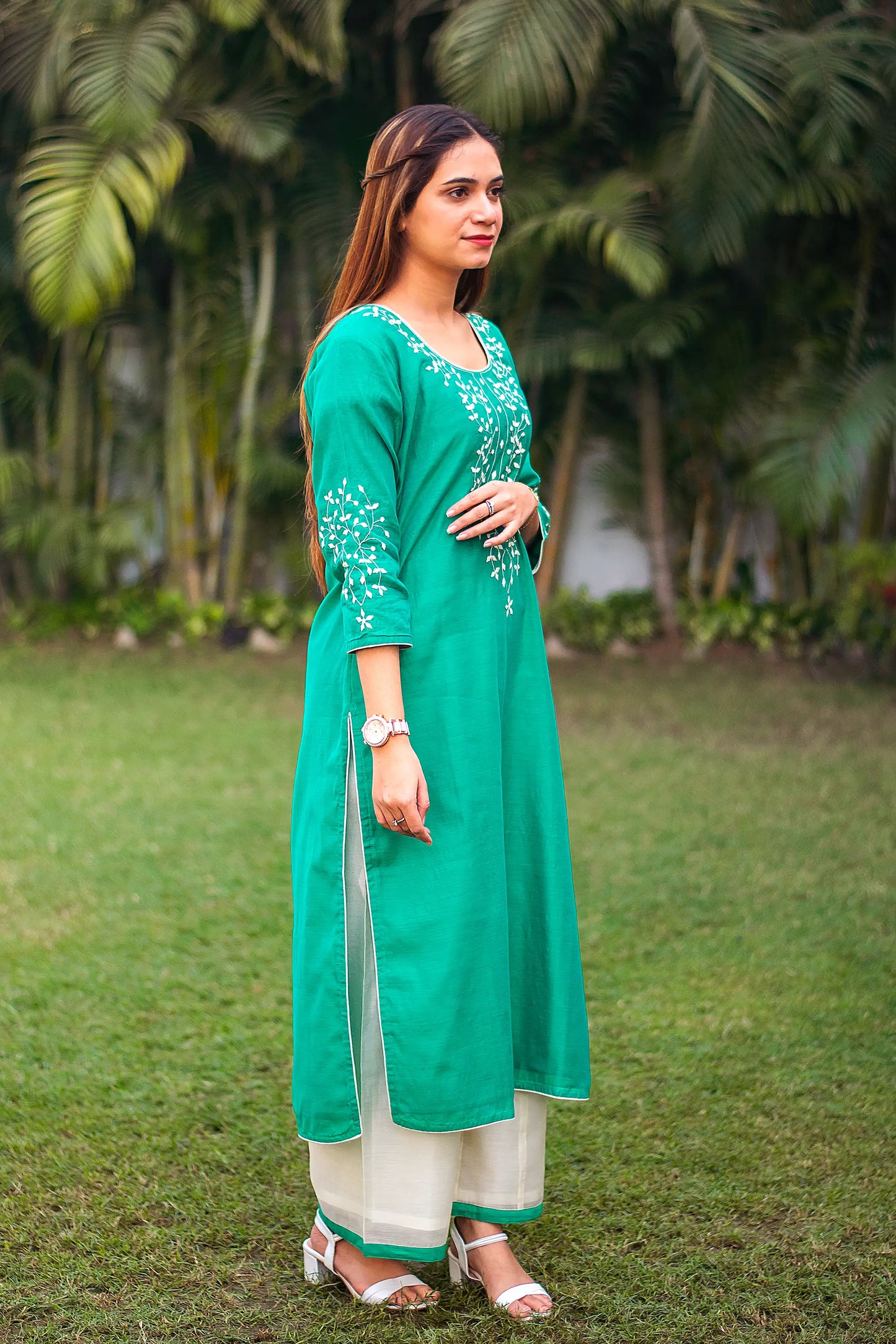 Full-length right side pose of an Indian girl wearing a green Chanderi kurta with applique work and white palazzo